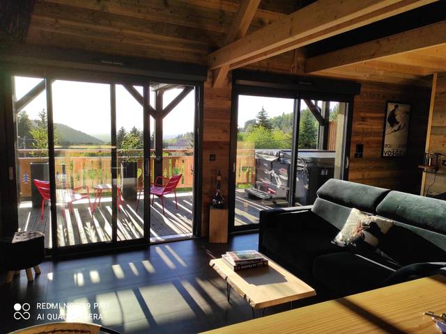 Salon lumineux ouvert sur terrasse panoramique - Chalet neuf avec jacuzzi privé, vue imprenable sur Massif des Vosges