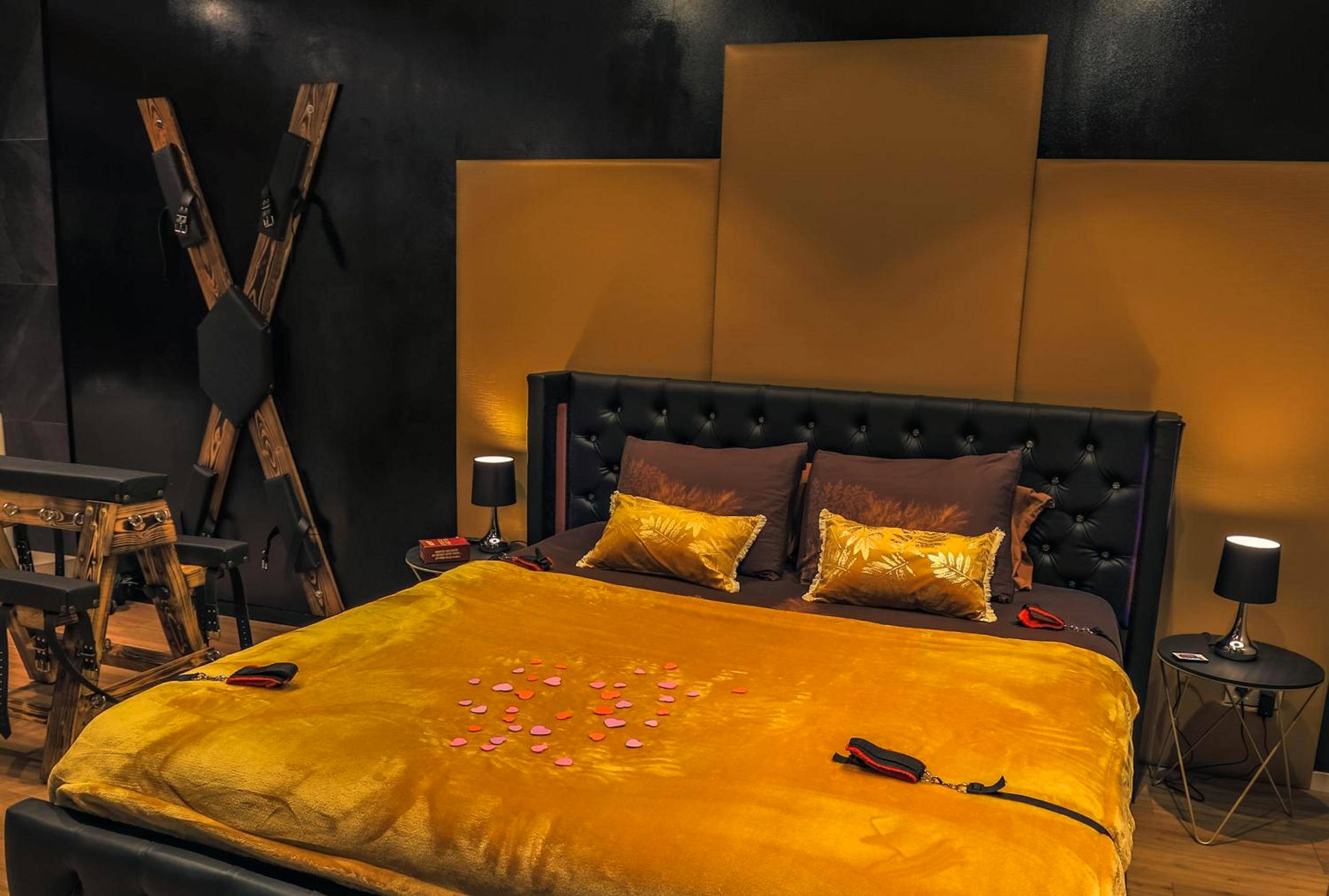 Lit double avec pétales de rose et croix de Saint - André - La loveroom bdsm grassoise "La chambre des désirs"