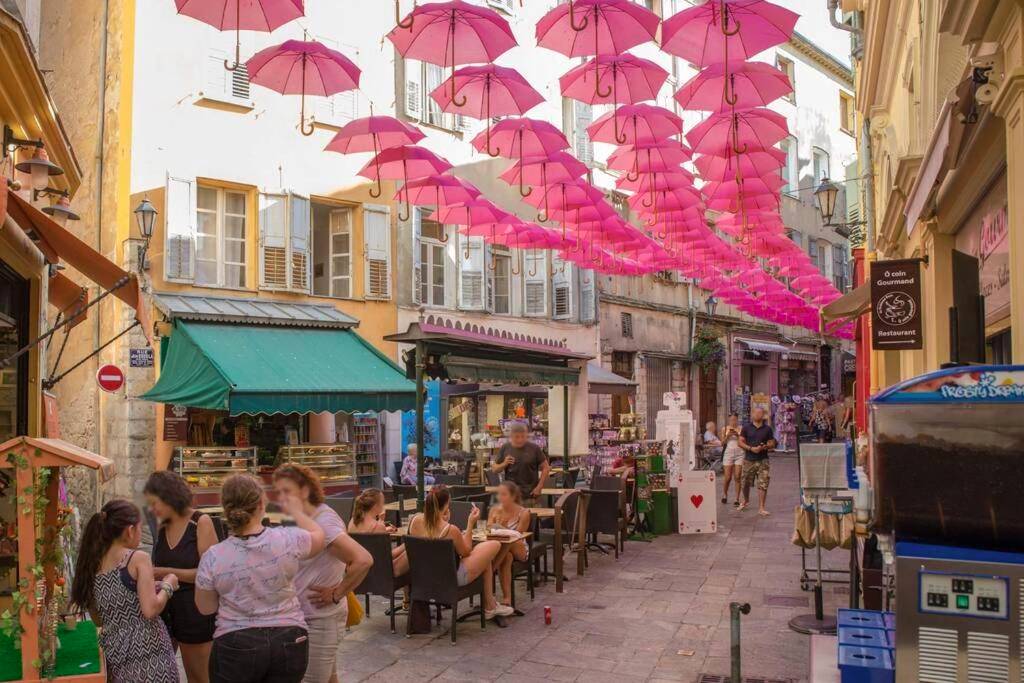 Rue piétonne décorée de parapluies roses - La loveroom bdsm grassoise "La chambre des désirs"