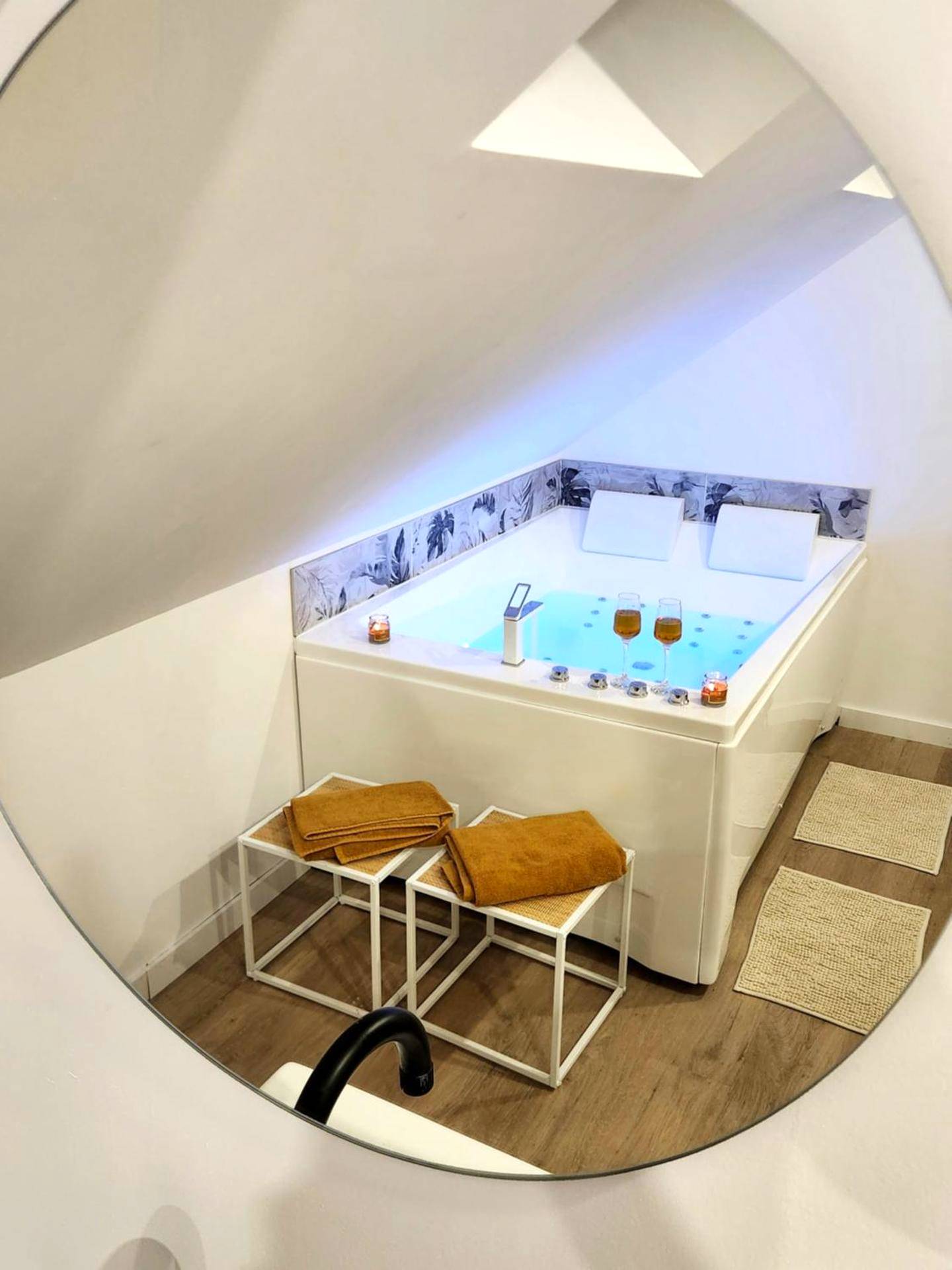 Baignoire balnéo vue à travers un miroir rond - Love Room Cambrai - Charme, détente sous les étoiles