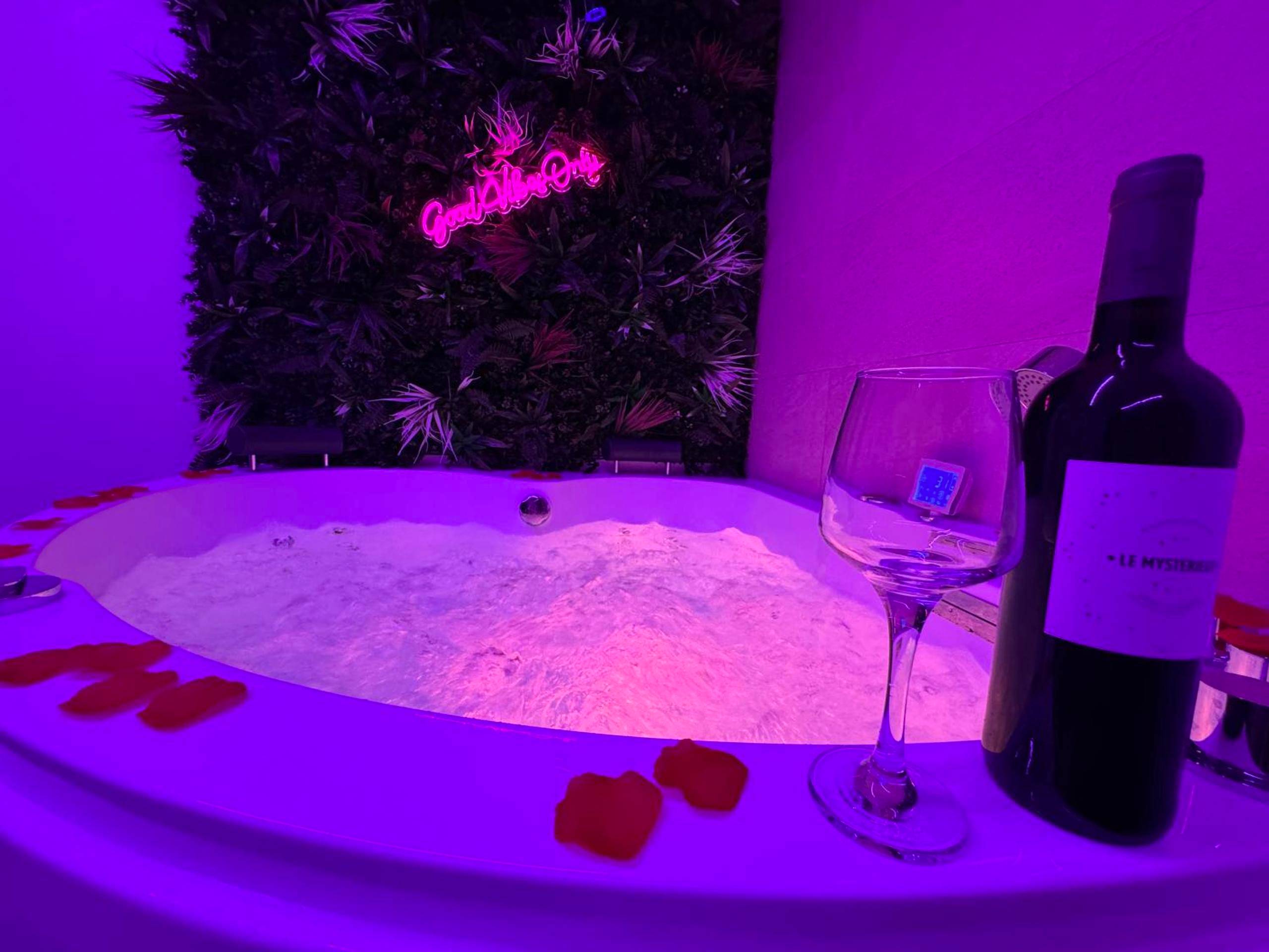 Jacuzzi avec pétales de rose et bouteille de vin - Love Room Cholet - Le Cinéma des Amants