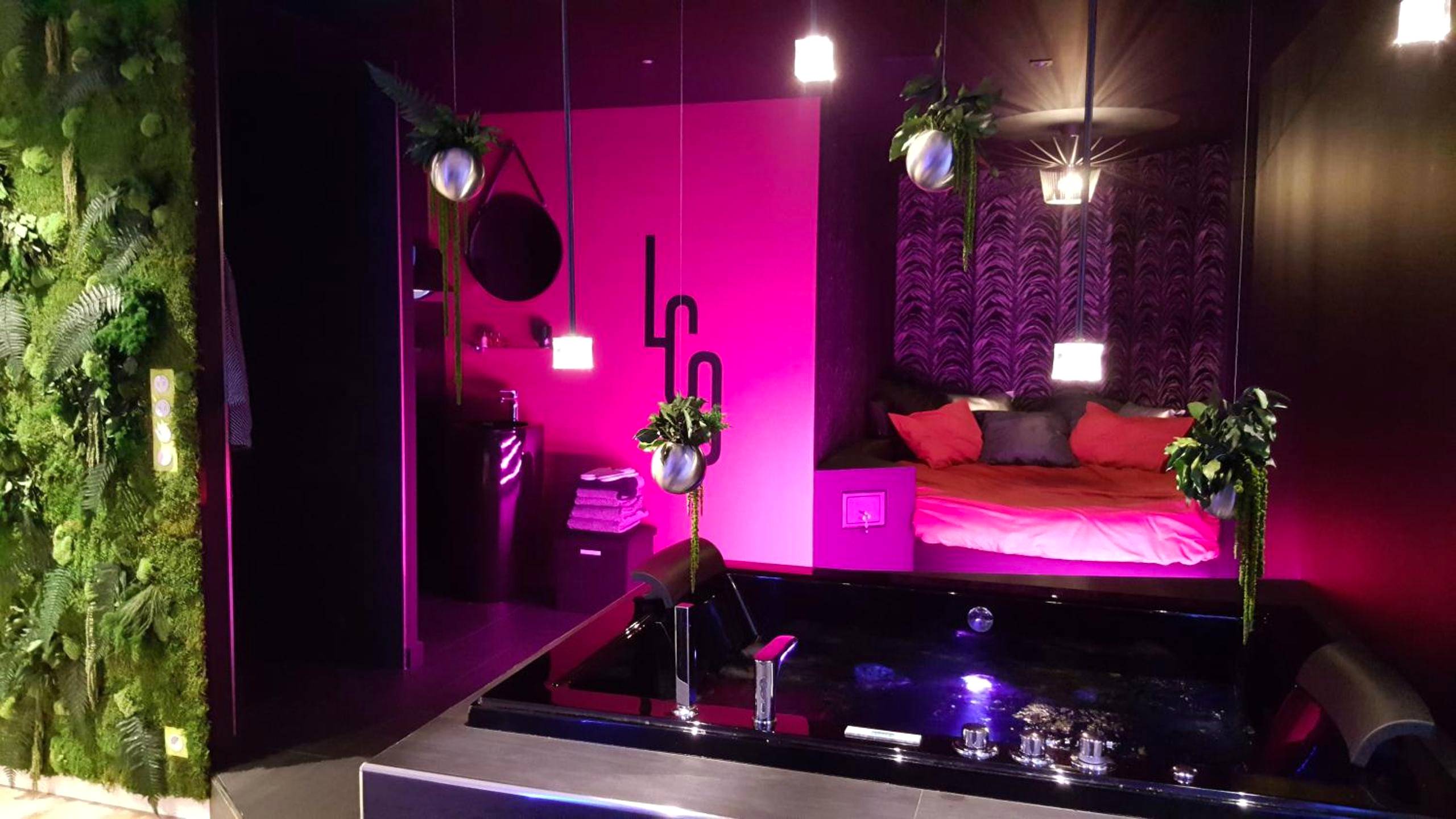 Jacuzzi noir et lit avec éclairage rose - Love Room Nantes - Le Clair Obscur
