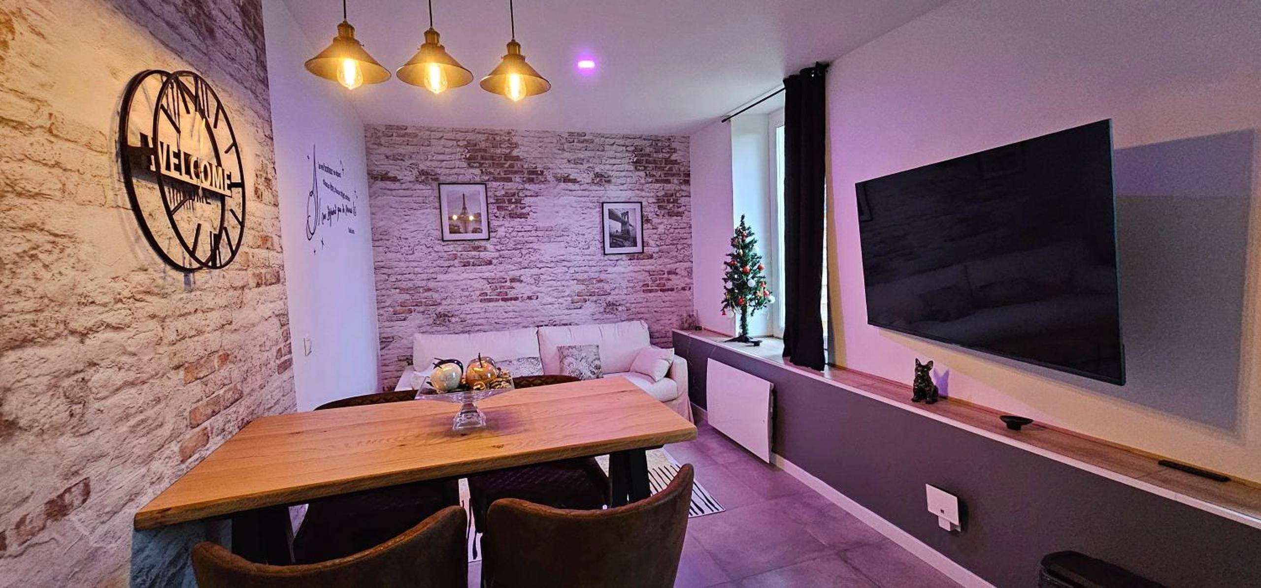 Espace séjour avec table en bois et grand écran - Le Clos Maldier - Gîte Les Ecureuils