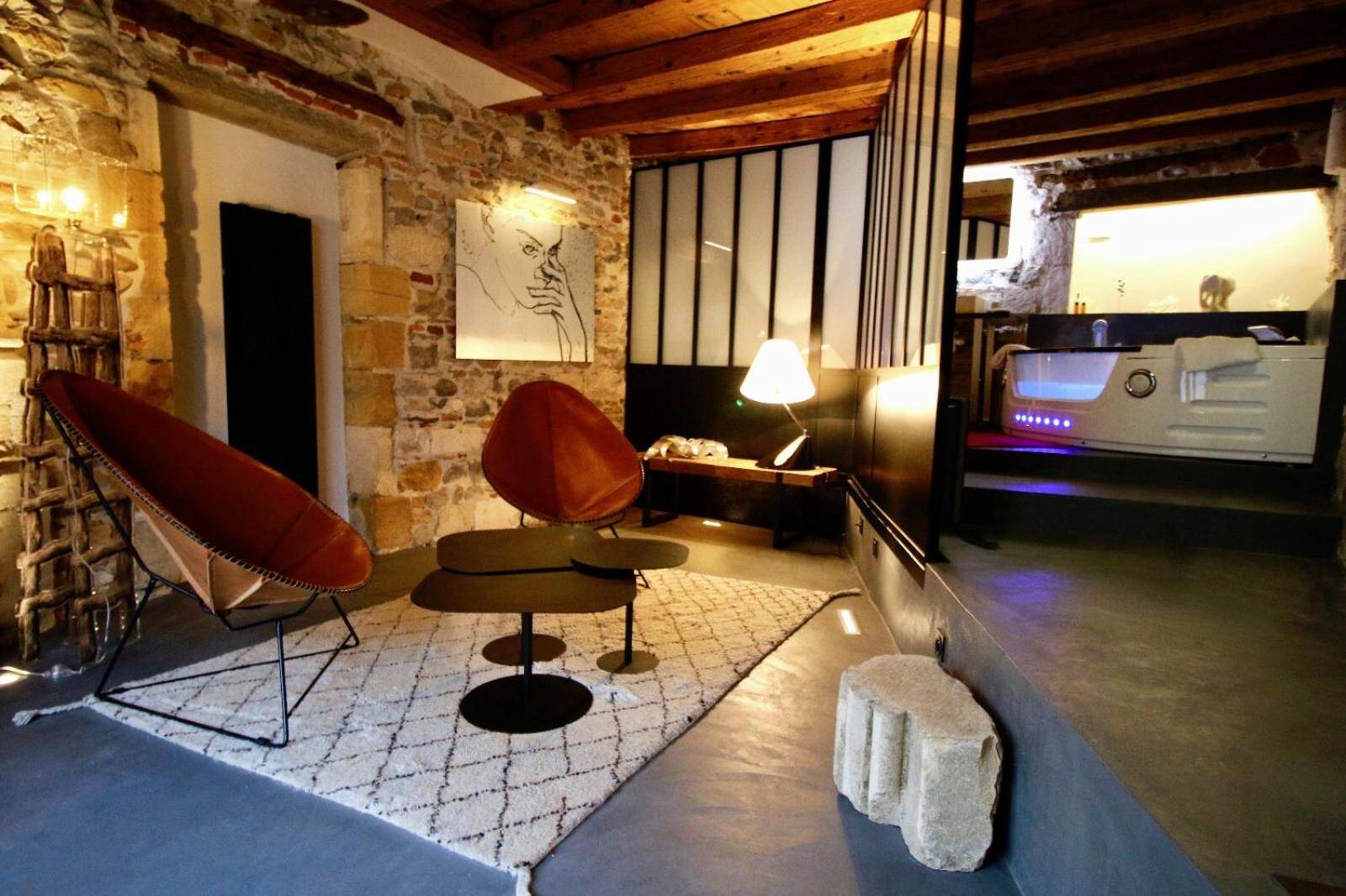 Salon avec fauteuils design et jacuzzi en fond - Love Room Lyon - Le Clos de Sainte Croix