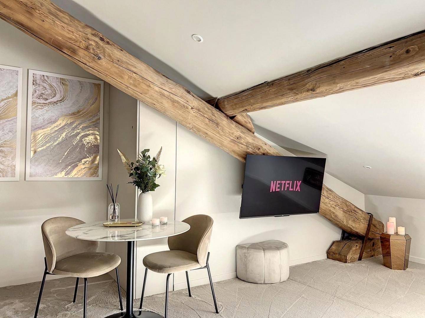 Espace repas et télévision sous poutres - Cocon Blanc câlin avec Jacuzzi privatif - LoveRoom Insolite
