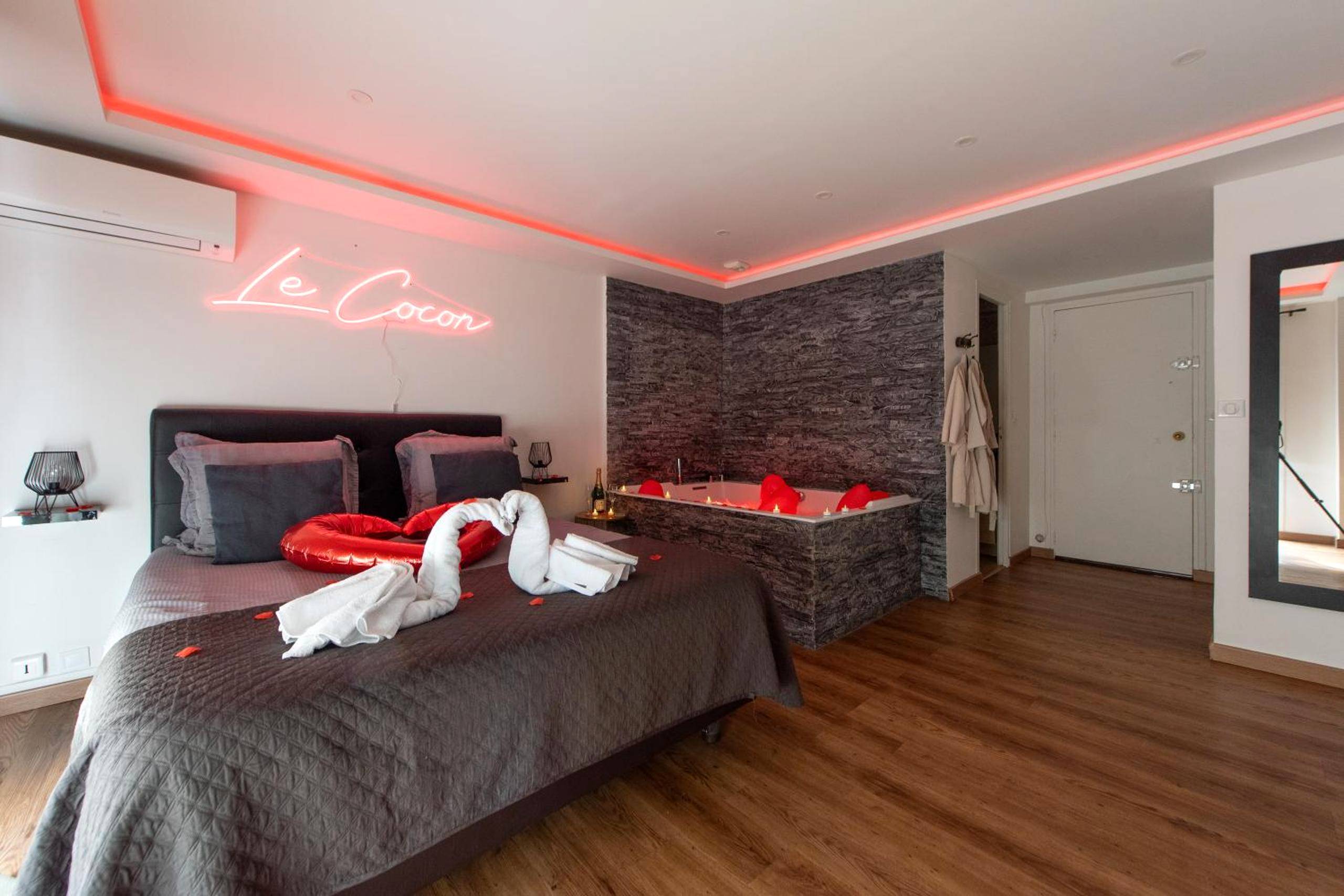 Lit avec cygnes en serviettes et néon rose - Love Room Le Cannet - LE COCON - Jacuzzi & Sauna privés By SweetDreams