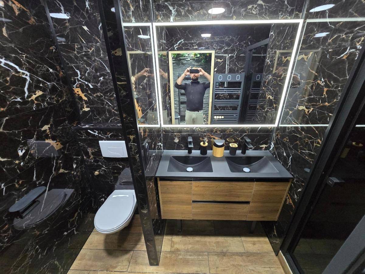 Salle de bain moderne en marbre noir et bois - Cocon Spa & Cinema Room