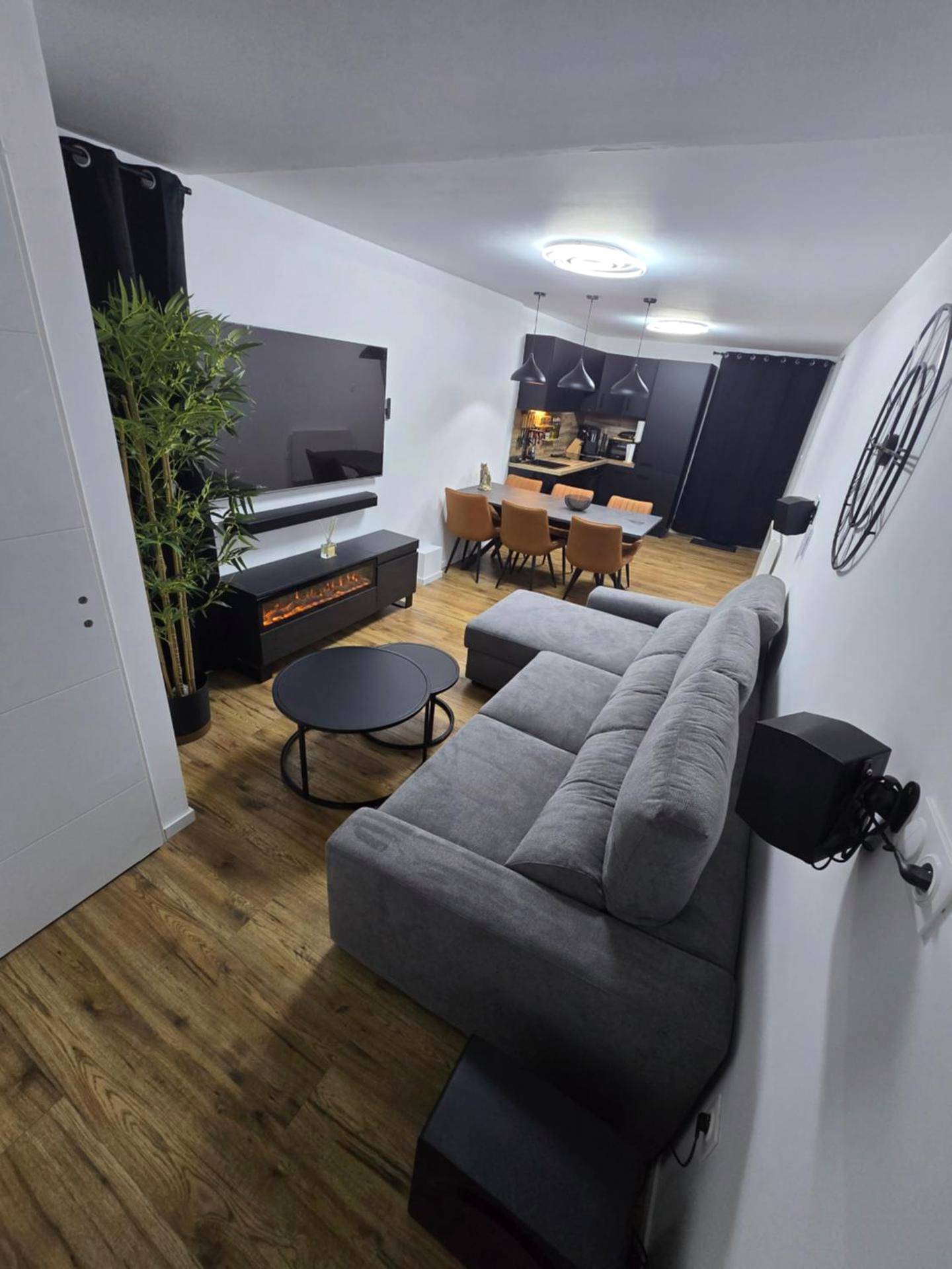 Salon avec canapé gris et cheminée électrique - Cocon Spa & Cinema Room