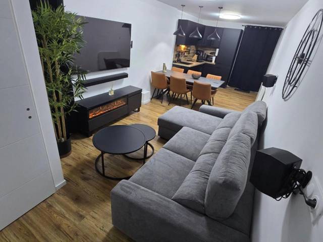 Salon avec canapé gris et cheminée électrique - Cocon Spa & Cinema Room
