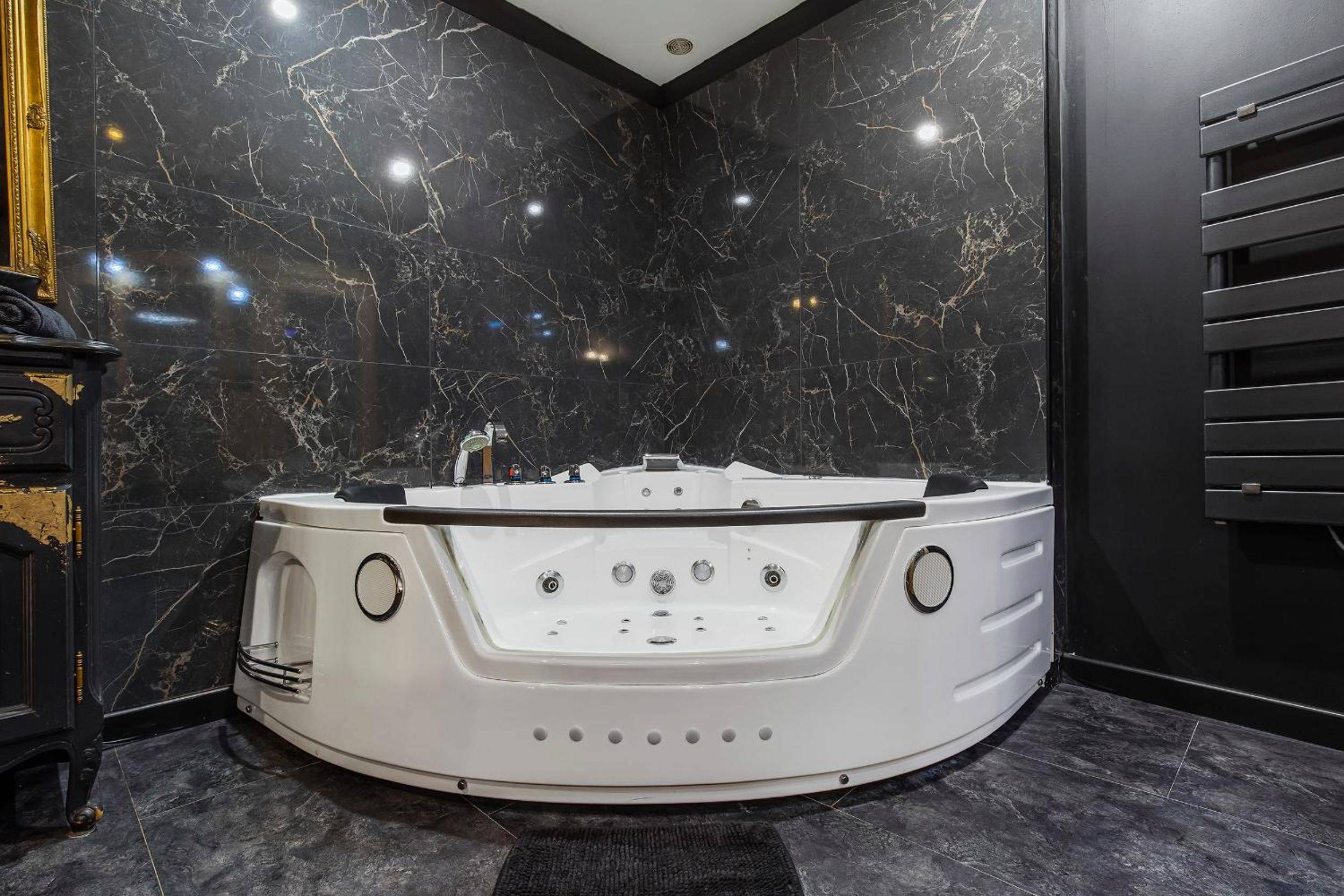 Baignoire balnéo devant un mur en marbre noir - COCONROOM balneo - sauna La suitE