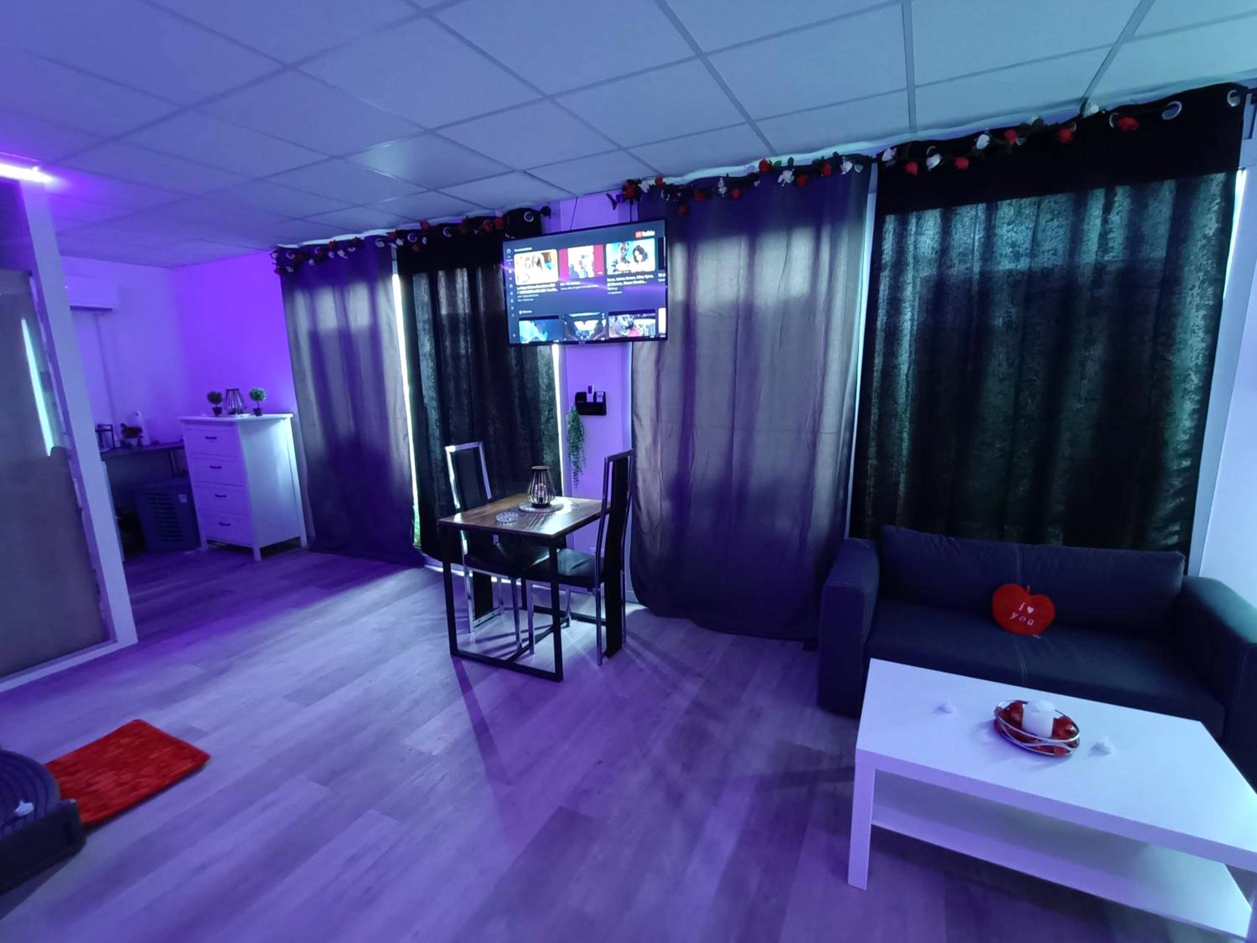 Salon avec canapé, table basse et coin repas - CocoonSPA LoveRoom Jacuzzi