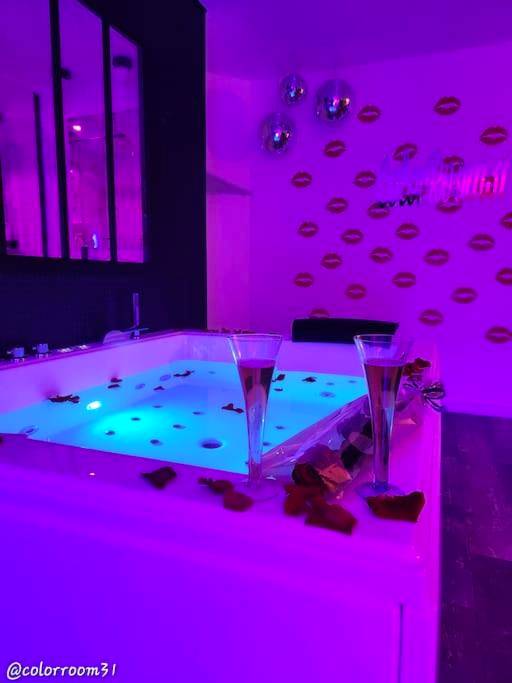 Jacuzzi avec flûtes et pétales sous néon violet - Love Room Rouffiac - Tolosan - Colorroom31 - Nuit insolite - Spa -...