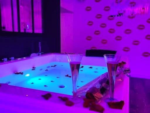 Jacuzzi avec flûtes et pétales sous néon violet - Love Room Rouffiac - Tolosan - Colorroom31 - Nuit insolite - Spa -...