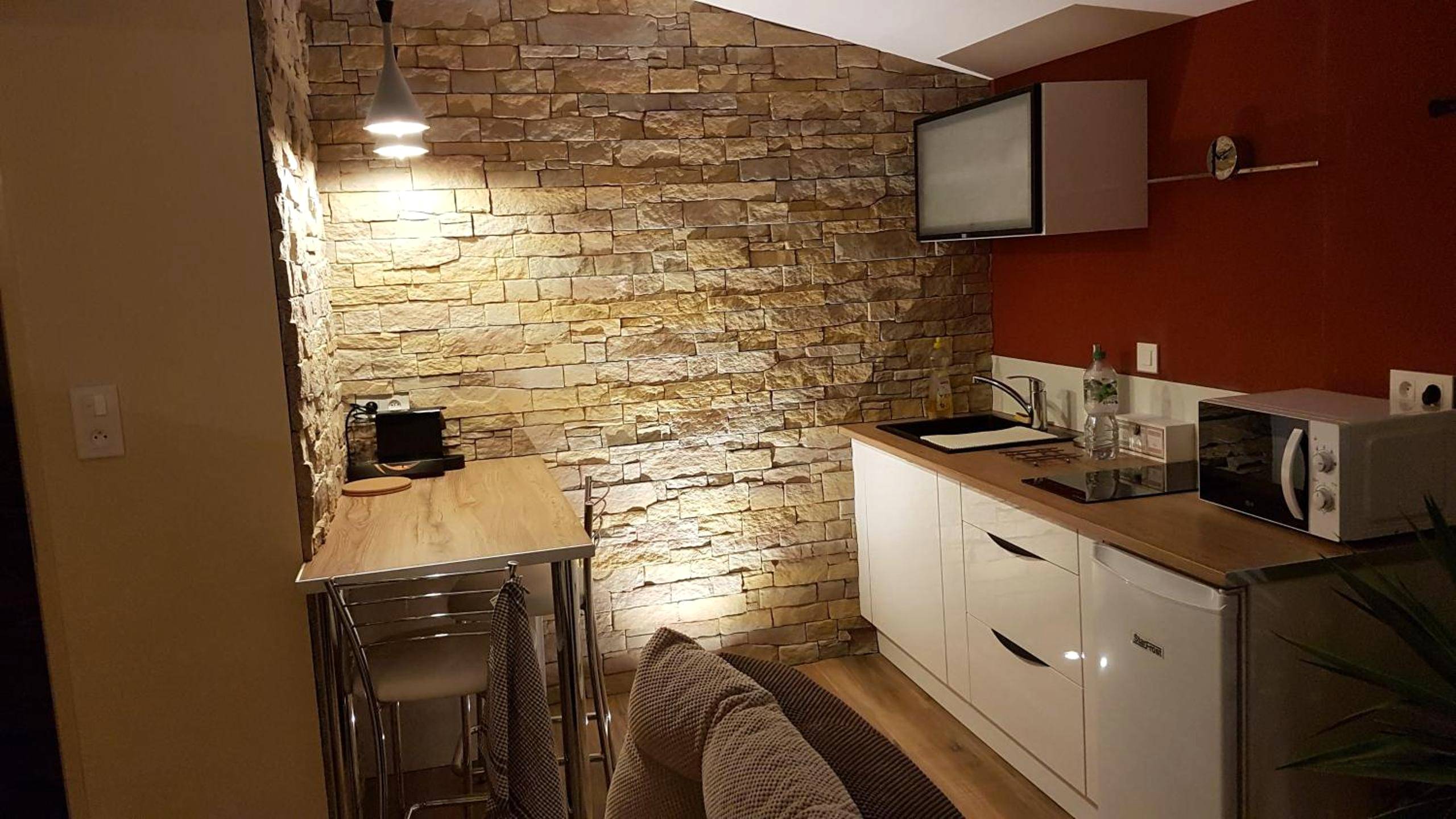 Coin cuisine équipée avec mur en pierre - Cosy Love & Spa Love room avec spa, hammam et sauna privatif