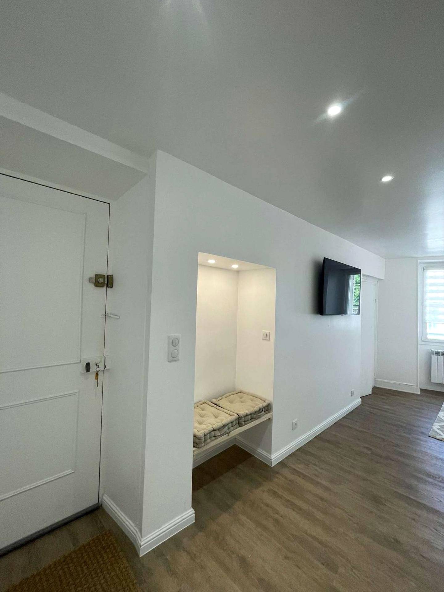 Entrée avec banquette intégrée et télévision - Appartement Dampierre en yvelines