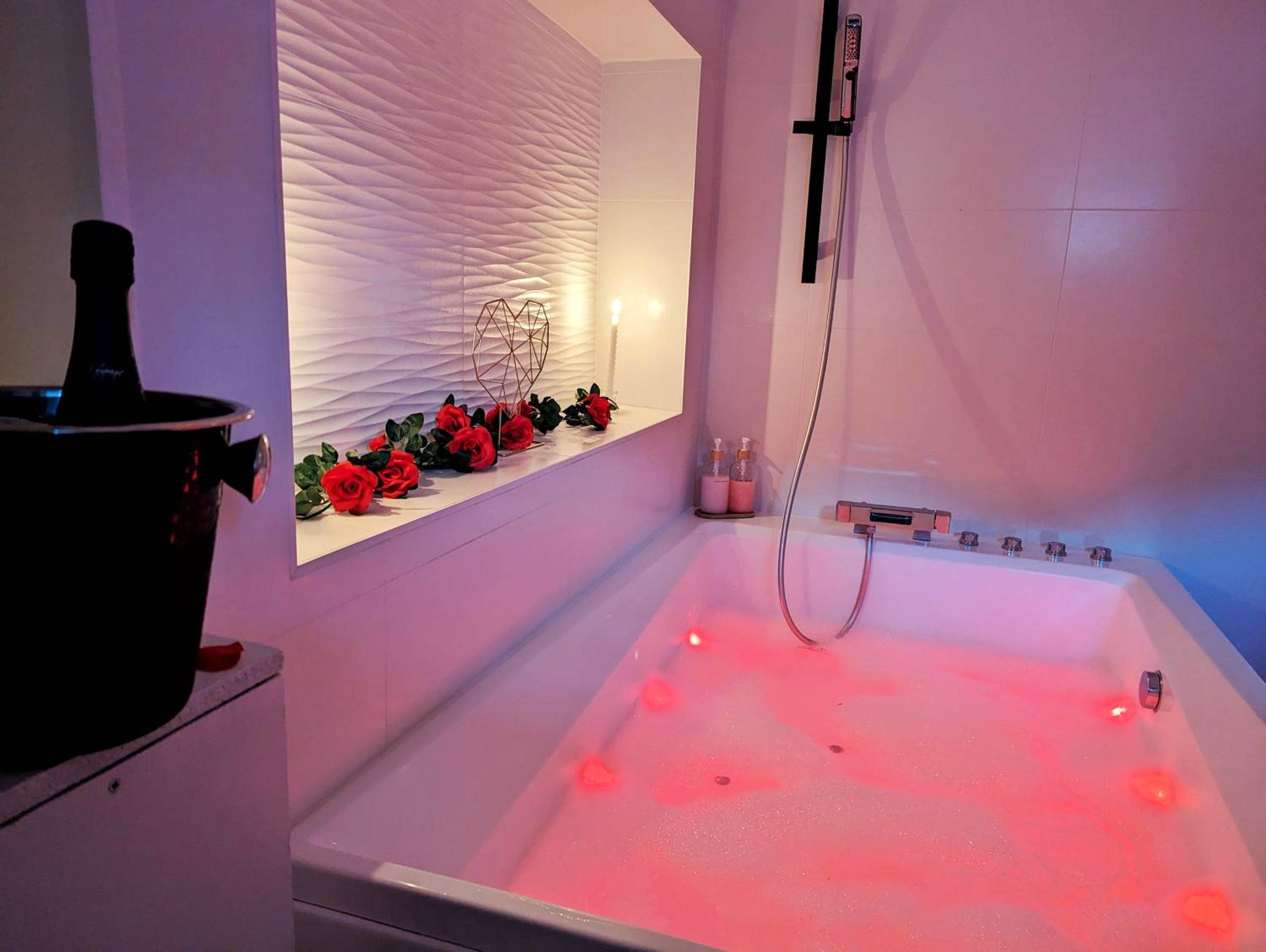 Baignoire balnéo avec éclairage rose et roses - Dark Room Perpignan aux 50 nuances Jacuzzi Privé