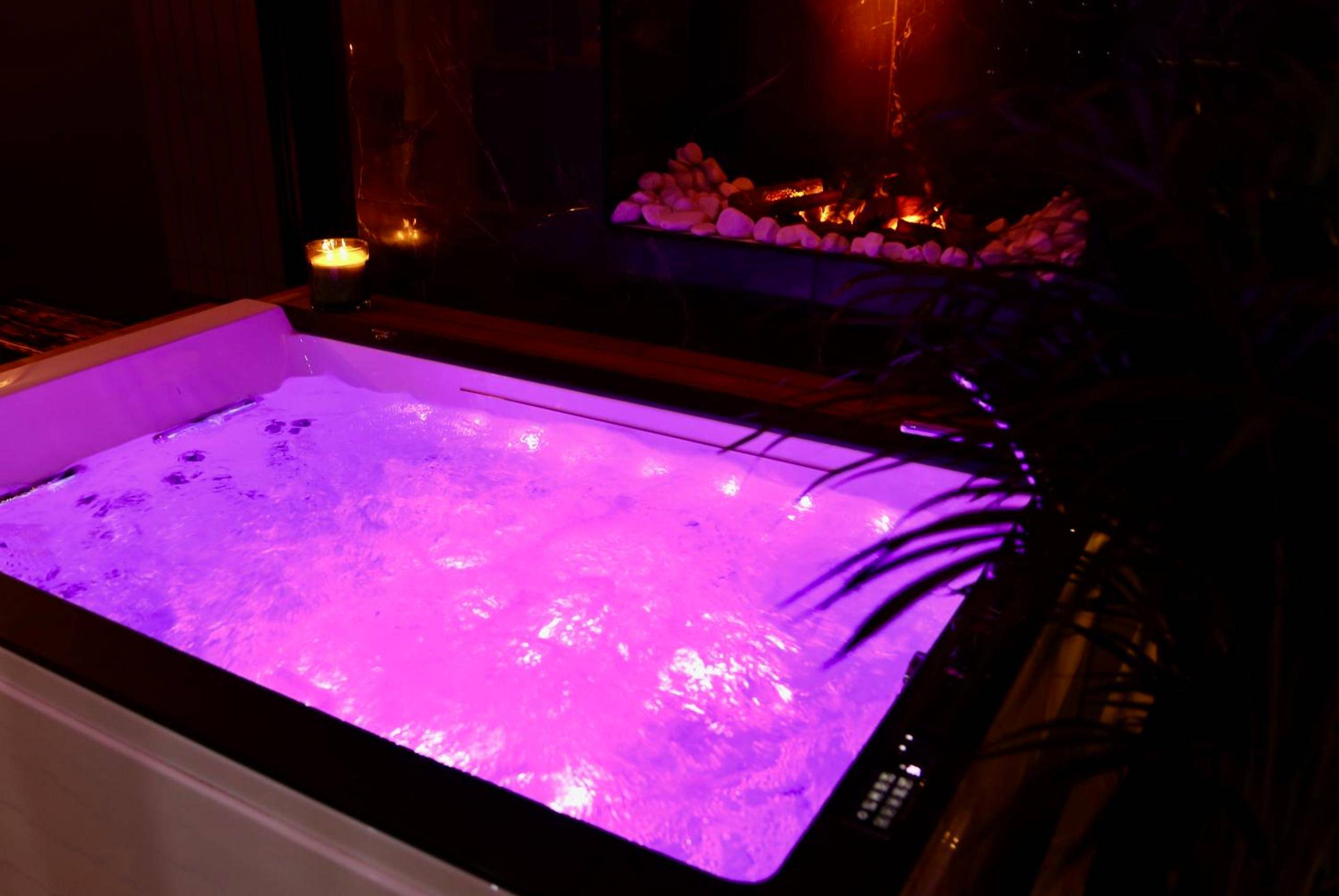 Jacuzzi privatif avec éclairage rose et bougie - Love Room Angers - love room gold - les delices rooms
