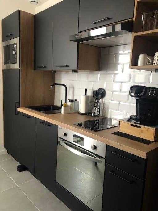 Cuisine équipée moderne aux tons noirs et bois - Le Diamant Secret Love room gîte de charme romantique exceptionnel