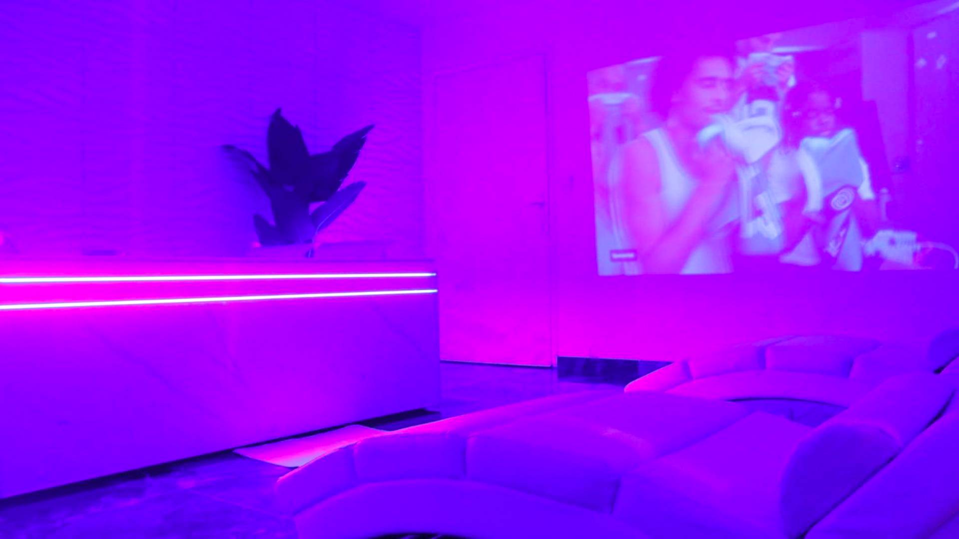 Vidéoprojecteur et banquette sous lumière néon - Love Room Vedène - DIMA SUITE Jacuzzi Privatif