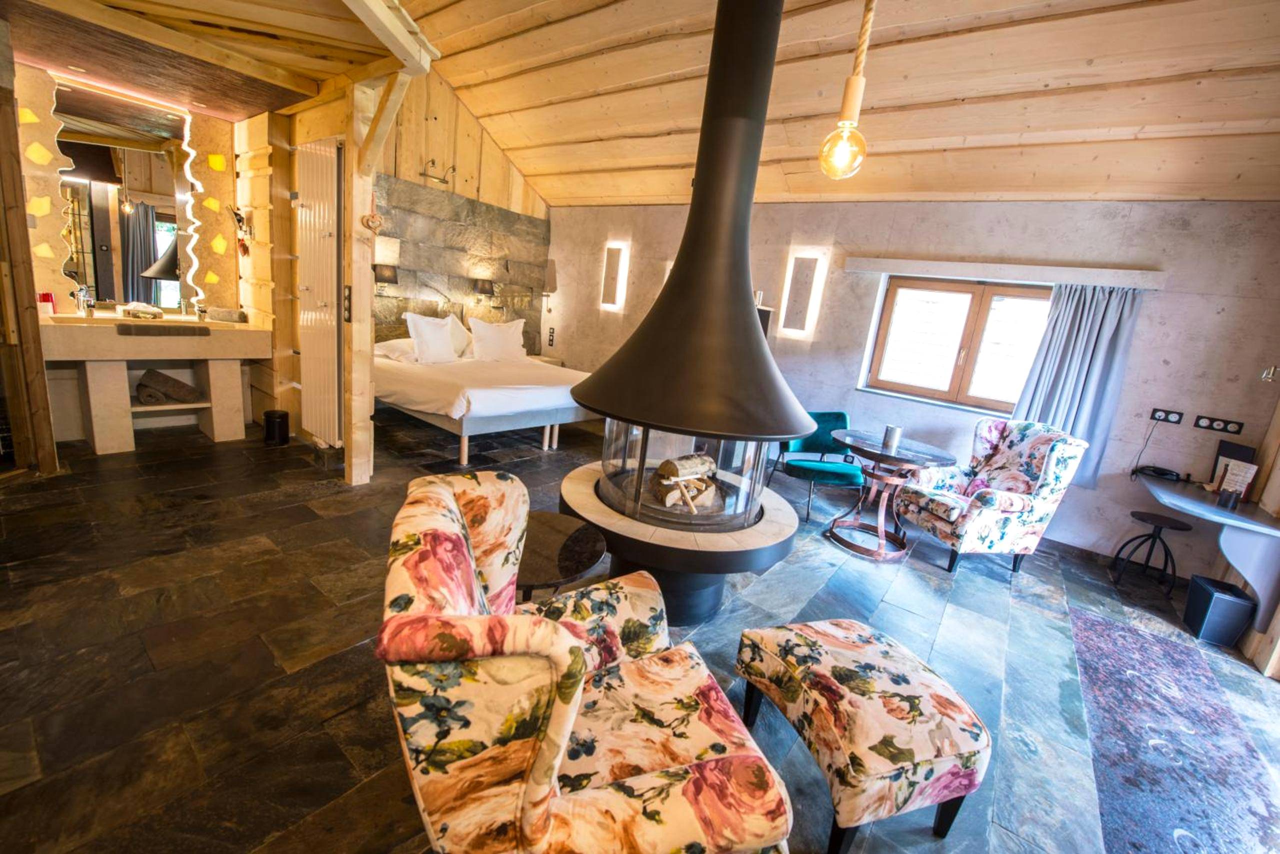 Suite avec cheminée centrale et fauteuils fleuris - Domaine du Haut Jardin Hôtel & Chalets Spa Privé