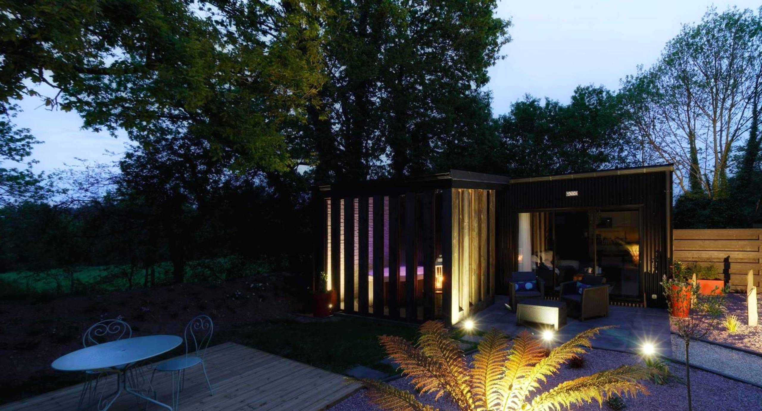 Vue nocturne du logement éclairé et jardin - La Douce Escapade