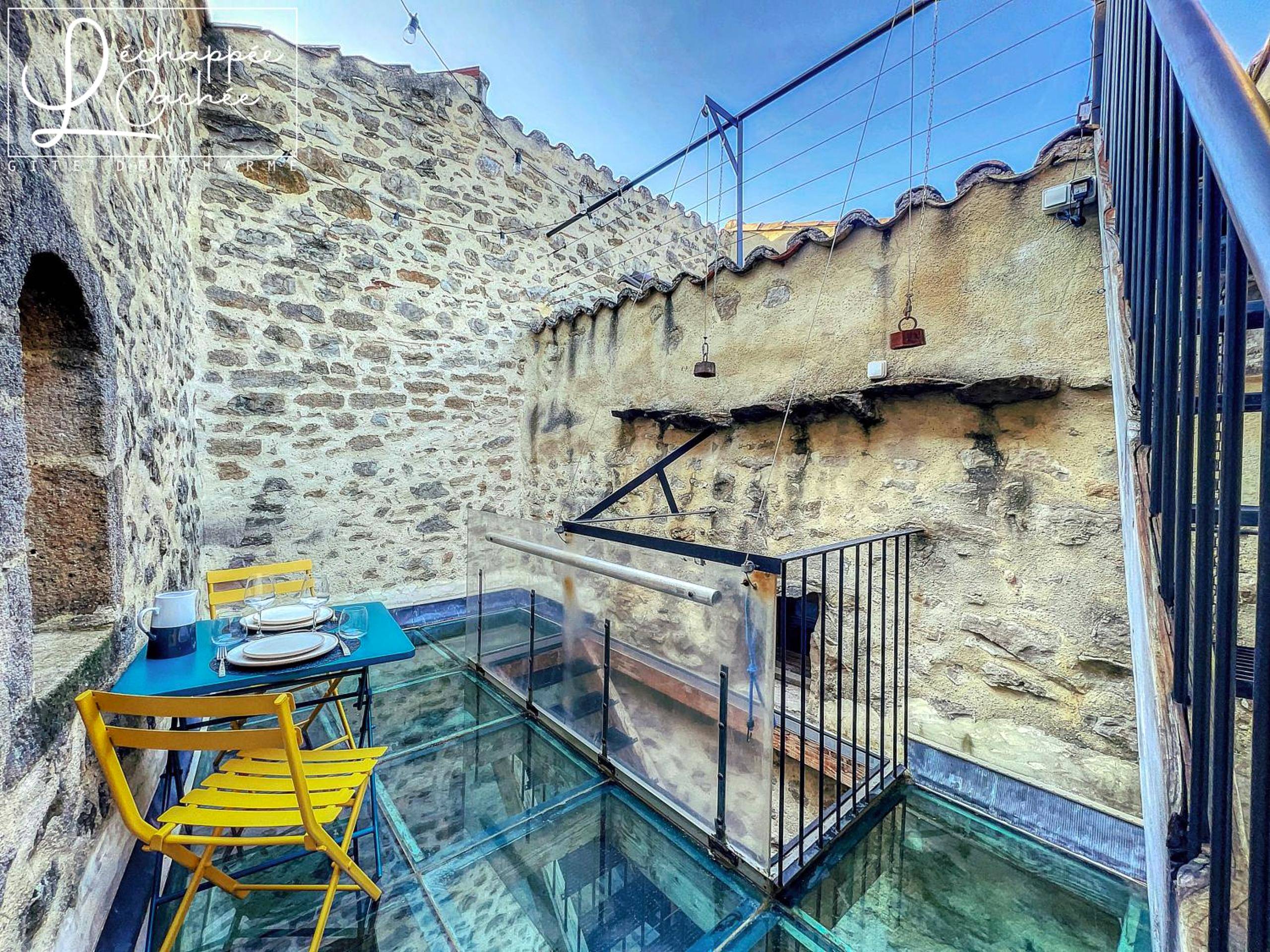 Terrasse avec sol en verre et table de repas - L’ Échappée Cachée - Gîte de Charme