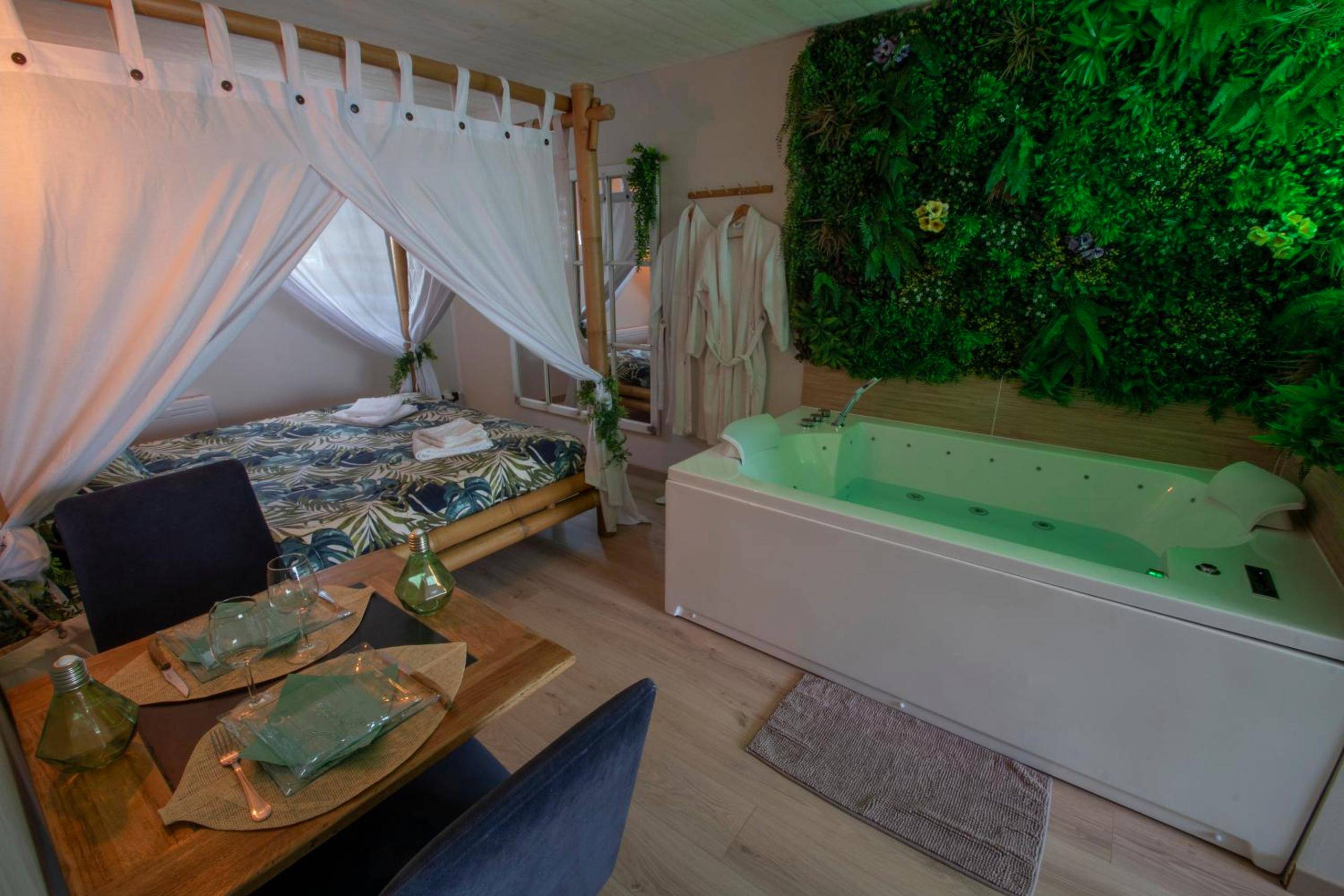 Jacuzzi et lit à baldaquin avec mur végétal - Love Room La Guérinière - L'échappée nocturne Nature et Zen