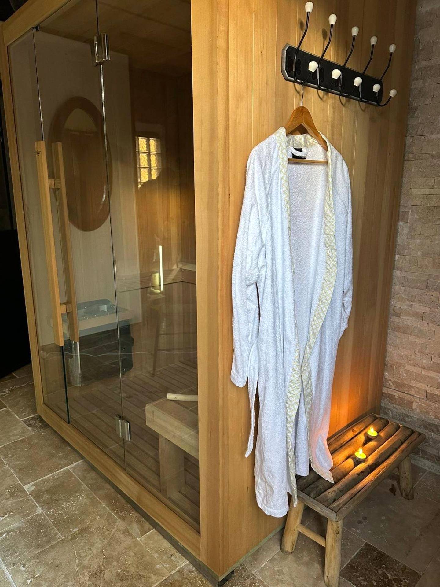 Sauna en bois vitré avec peignoir blanc - L'Écrin de l'Amour