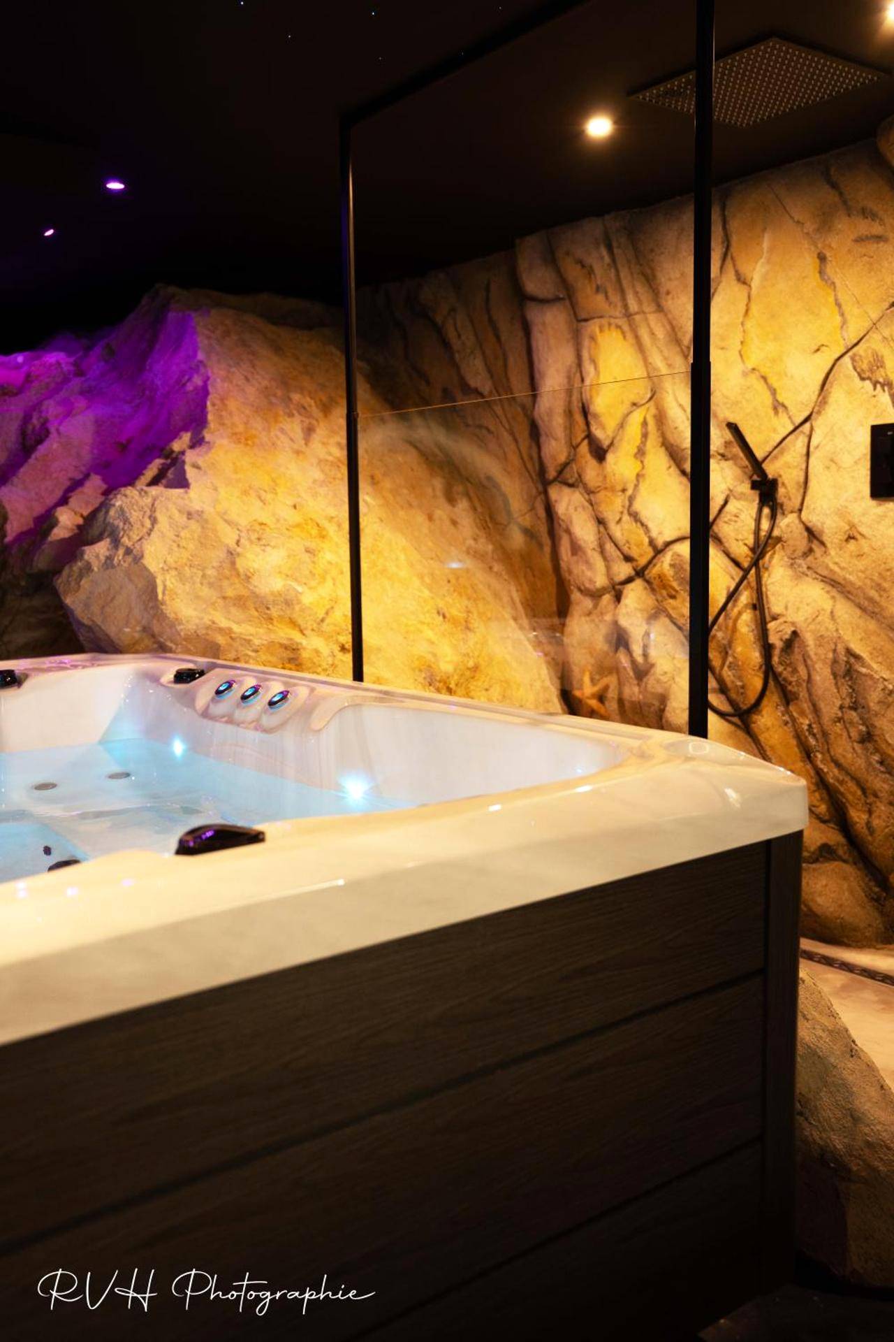 Jacuzzi privatif devant un mur de roche - Love Room L'ecrin d'Asteria