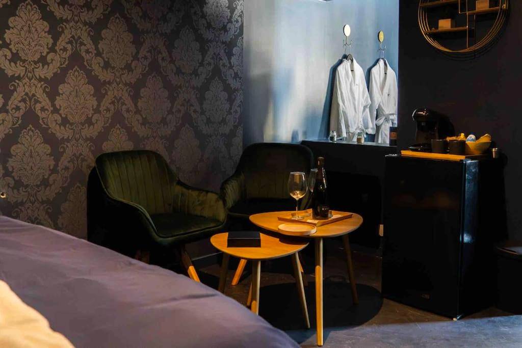 Coin salon avec fauteuils en velours et peignoirs - Loveroom En Aparté Caen