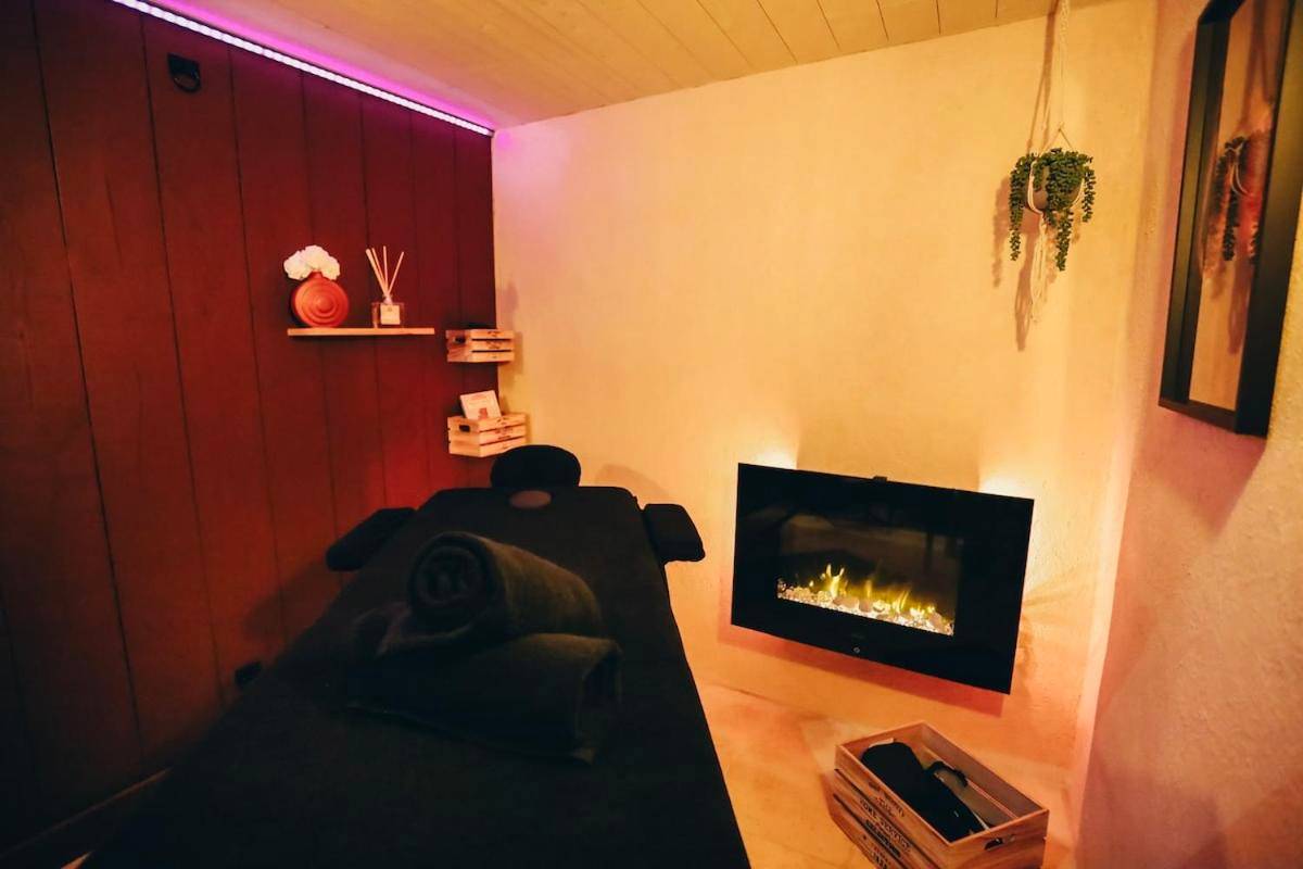 Table de massage face à une cheminée murale - Love Room L'Entre Nous