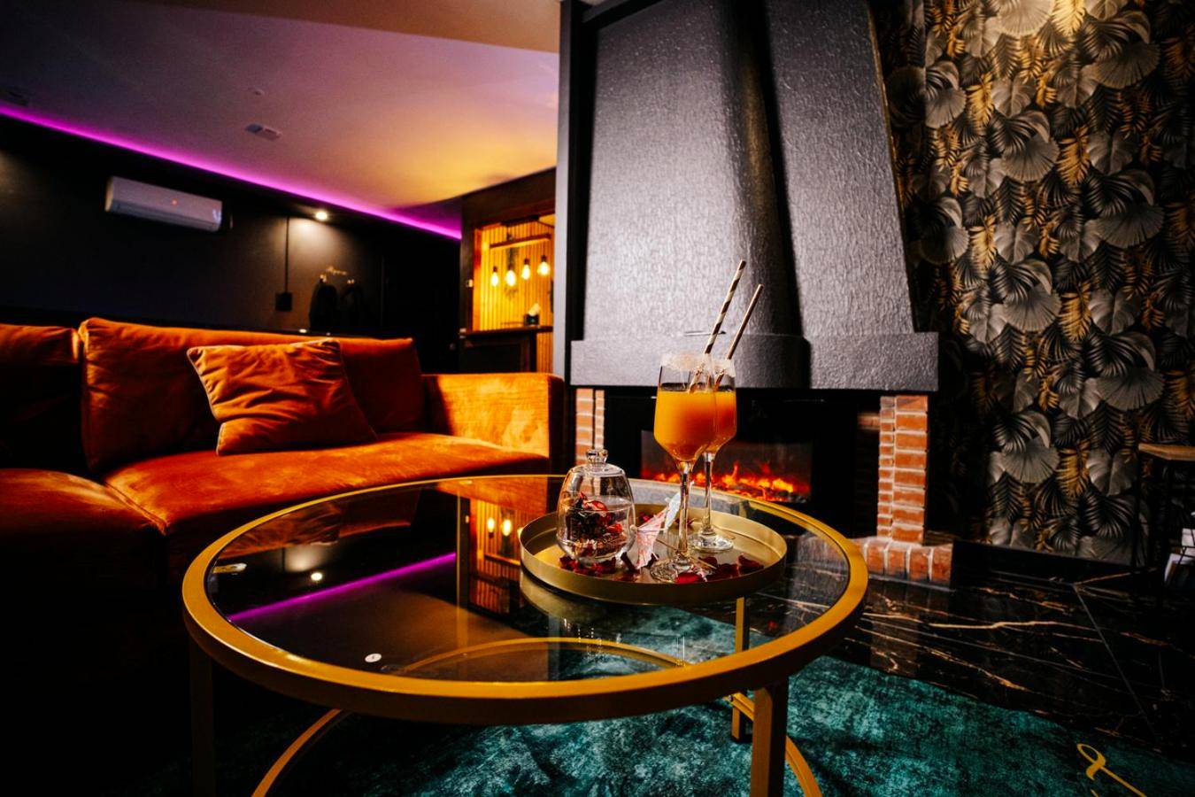 Salon avec canapé en velours et cheminée - L escale Jacuzzi et Sauna