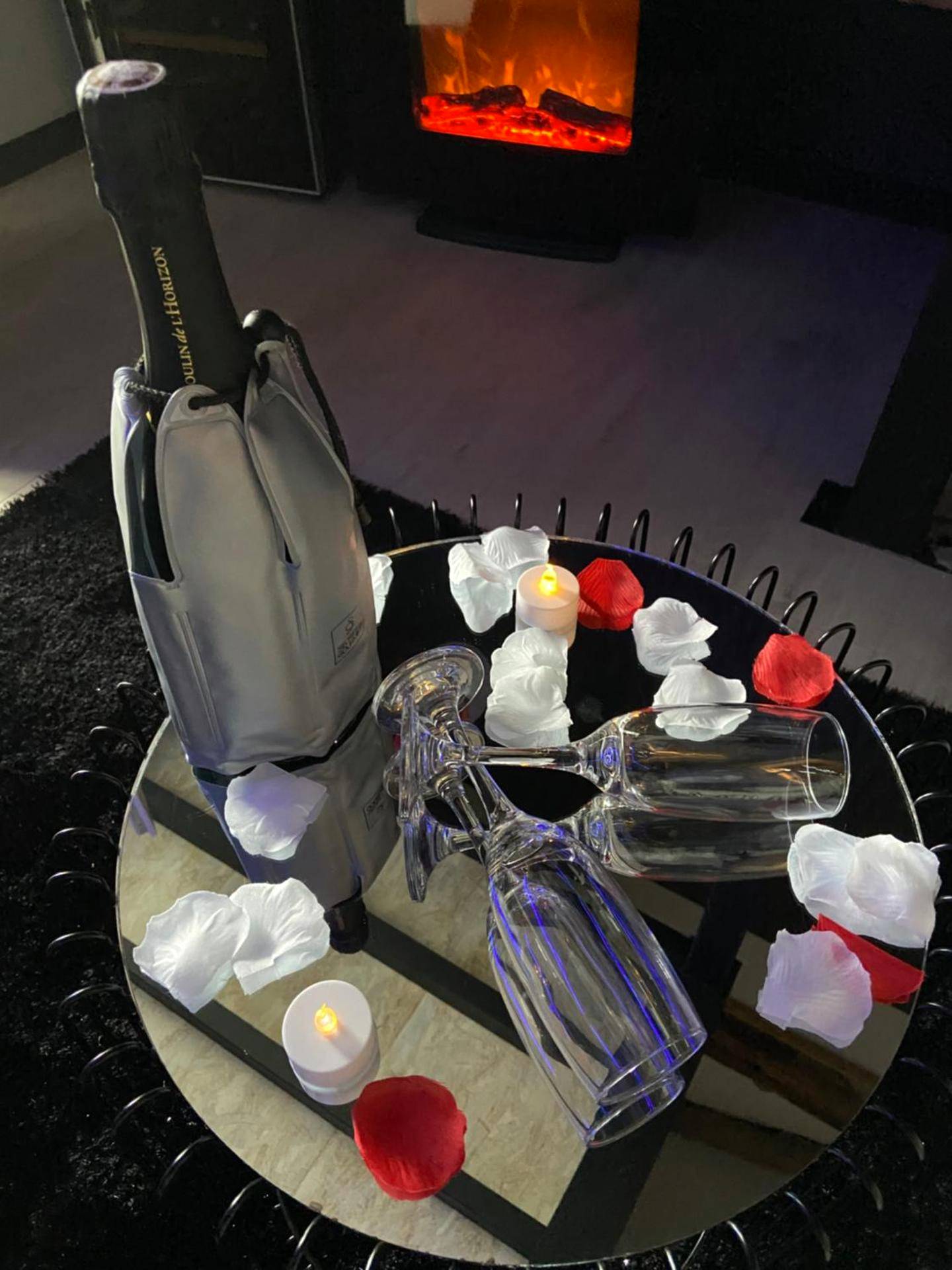 Champagne et pétales sur table devant cheminée - L escapade amoureuse