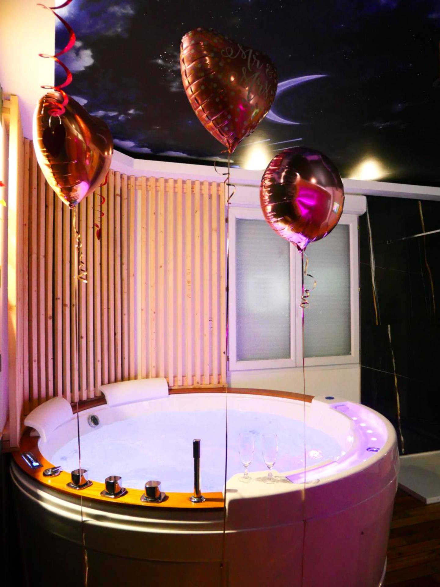 Jacuzzi rond avec ballons et plafond étoilé - Love Room Calais - L'Escapade Inattendue