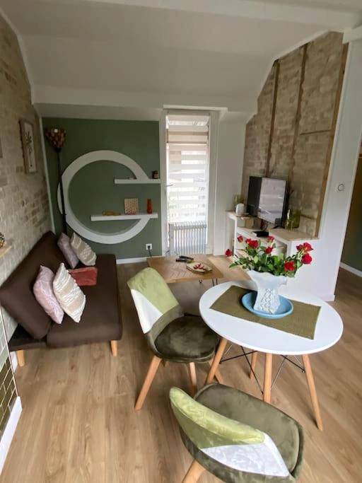 Salon avec canapé, table ronde et fleurs - L'Escapade Inattendue