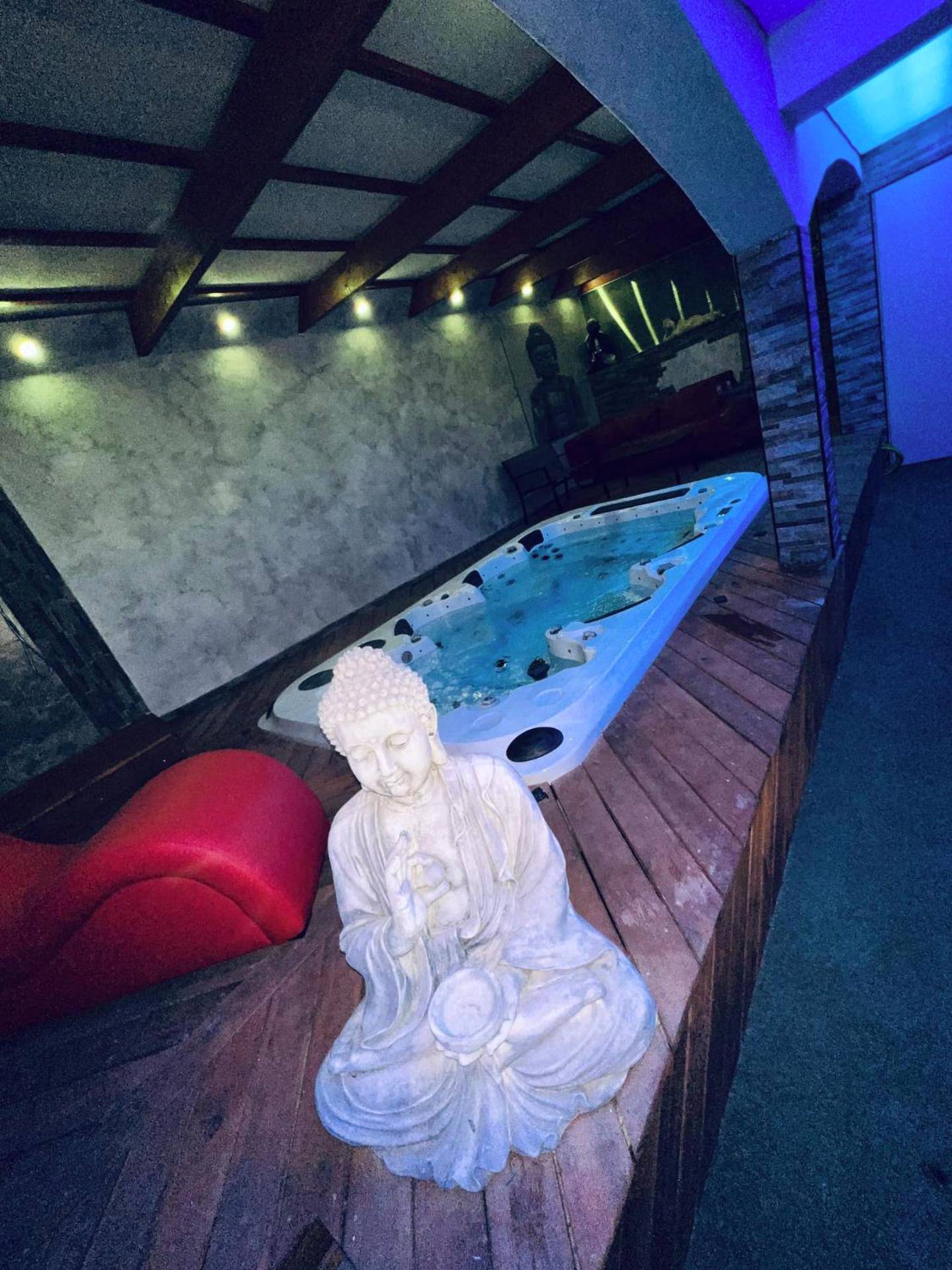 Jacuzzi encastré avec statue Bouddha et sofa rouge - Love Room Espondeilhan - Appartement Romantique L'Escapade Jacuzzi