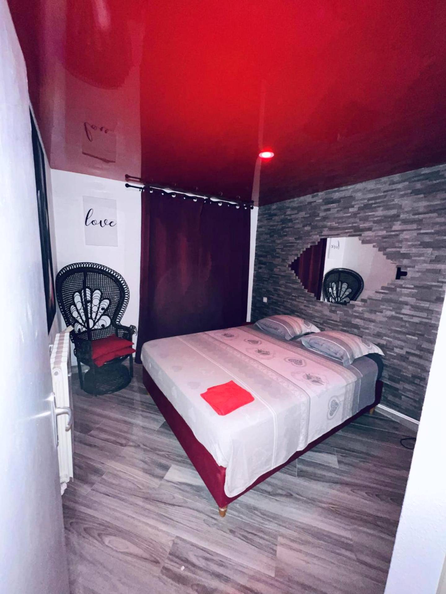 Chambre avec plafond rouge et fauteuil Emmanuelle - Appartement Romantique L'Escapade Jacuzzi