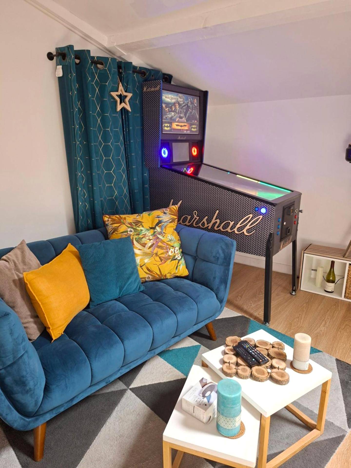 Salon avec canapé bleu et flipper vintage - Nuit Romantique, Spa, Champagne, Cinéma, Flipper - Escapade Veyloise