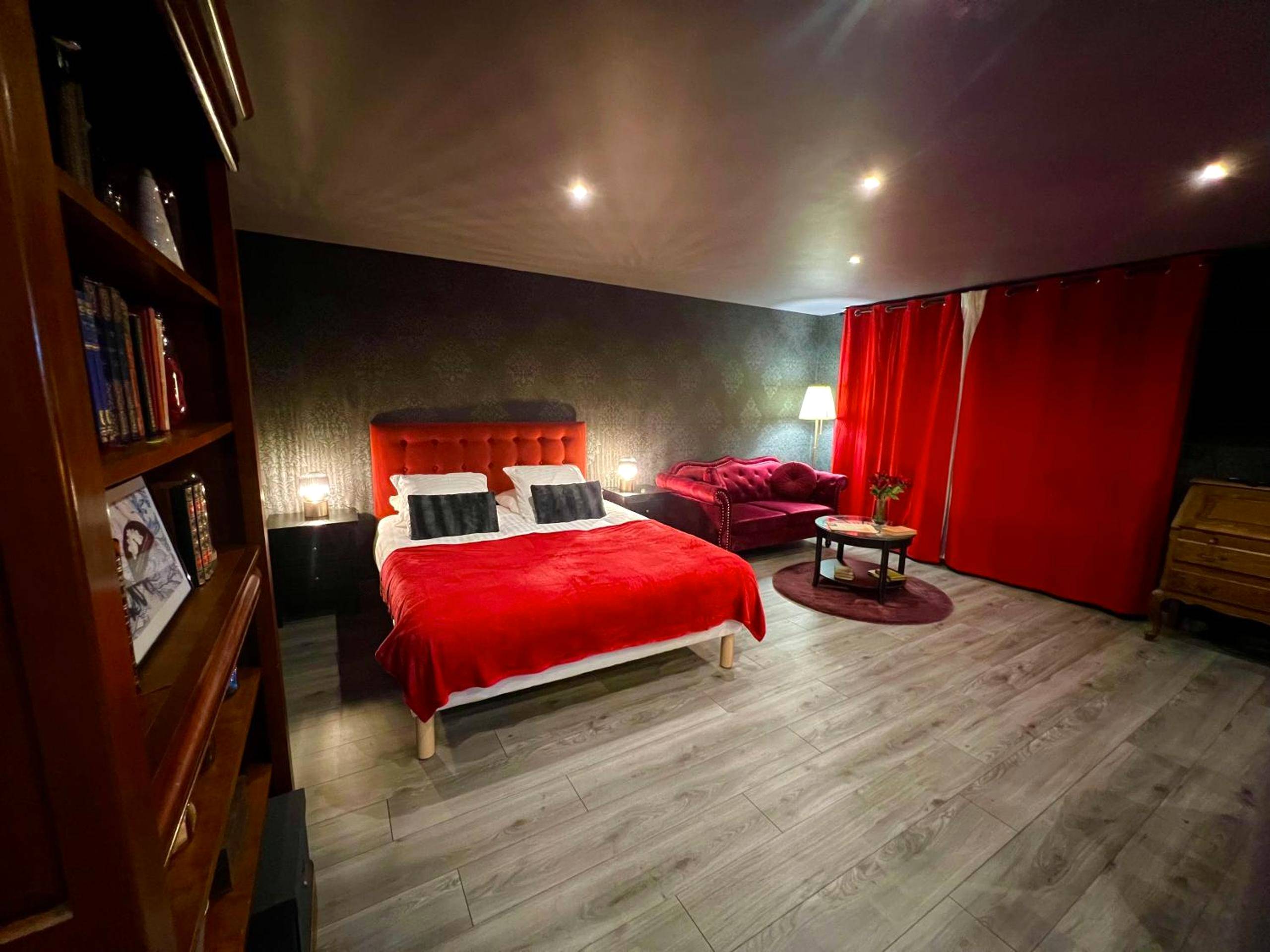 Lit double avec jeté rouge et rideaux assortis - Love Room Calais - L'Escape
