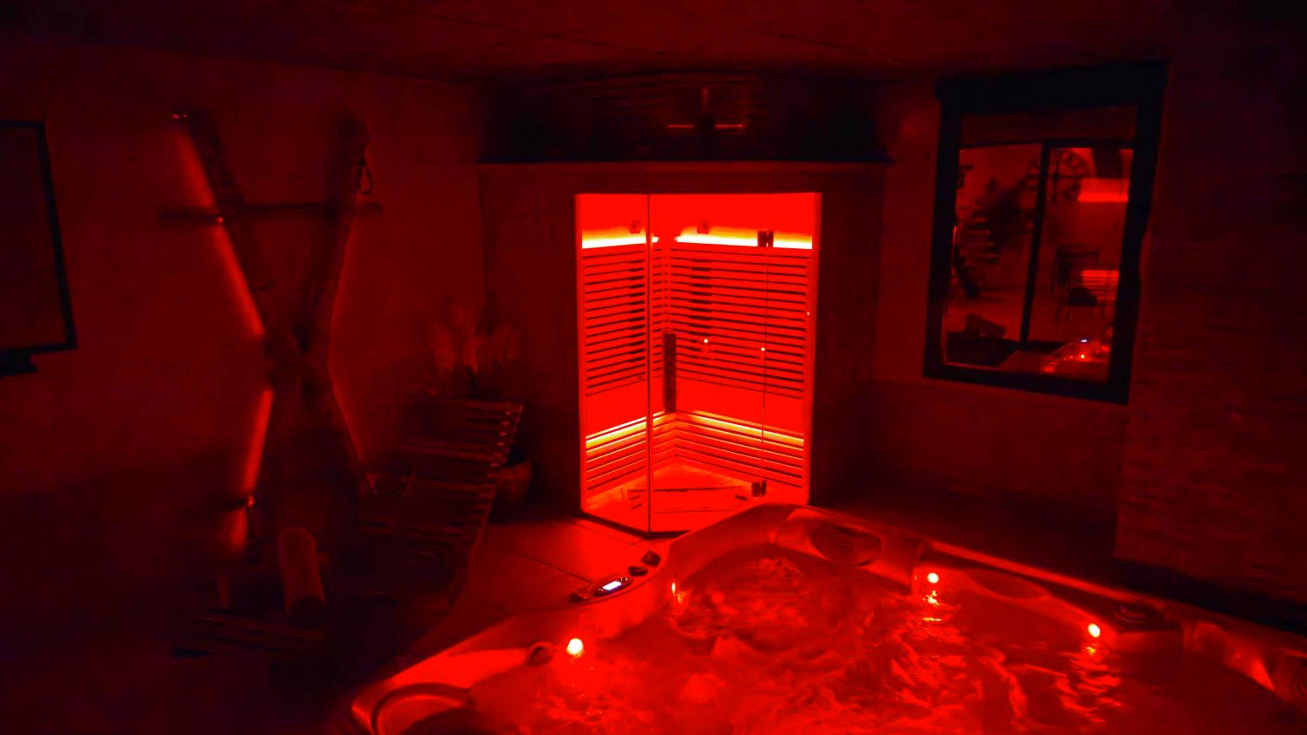 Jacuzzi et sauna sous lumière rouge tamisée - Espace évasions Loft Kis LOVE ROOM