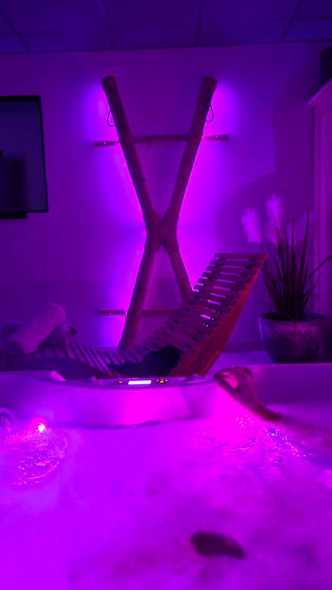 Jacuzzi et croix de Saint - André en lumière violette - Espace évasions Loft Kis LOVE ROOM