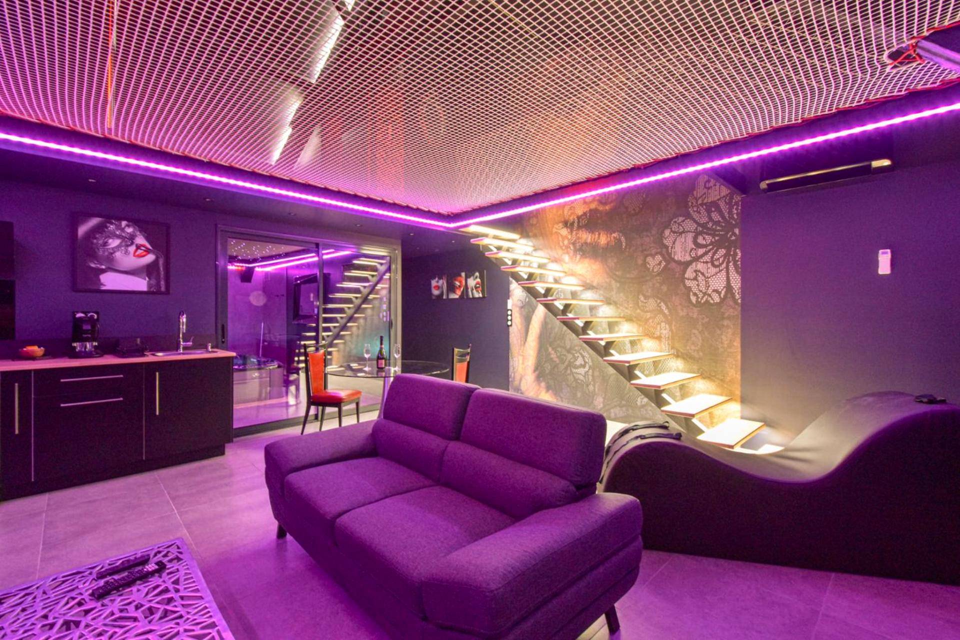 Salon avec canapé violet et fauteuil tantra - Espace évasions Loft love LOVE ROOM