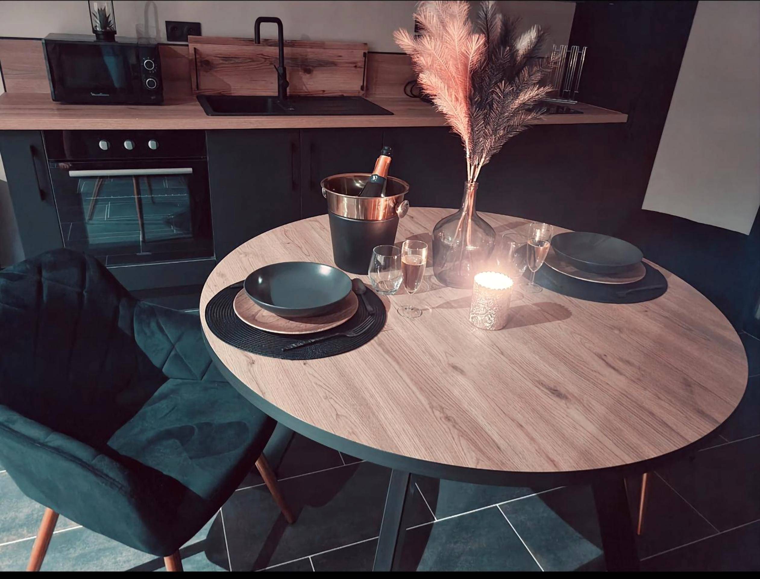 Espace repas avec table ronde et cuisine équipée - Les étonnants romantiques