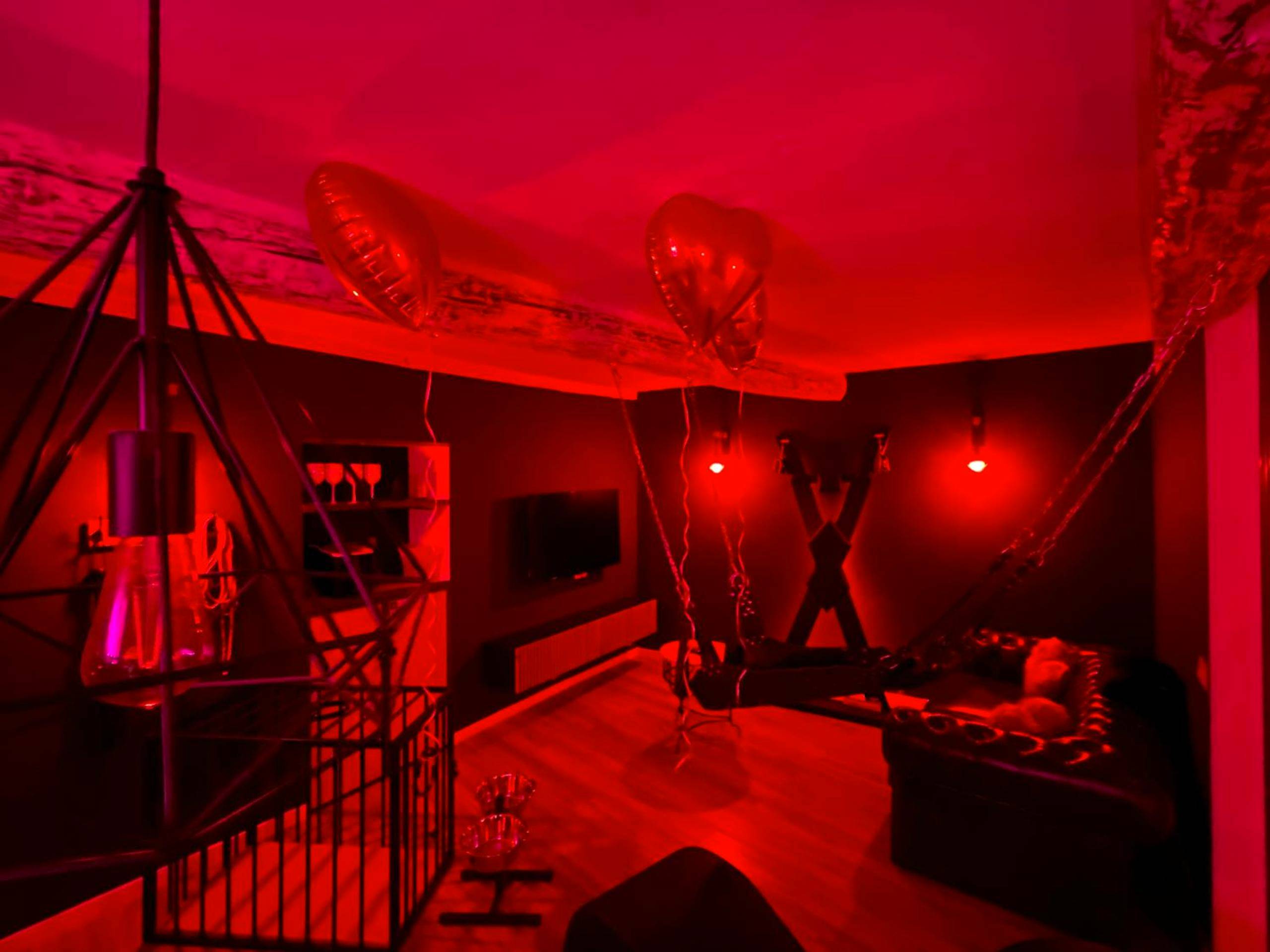 Ambiance tamisée rouge avec cage et mobilier - L’Evasion la Love Room de Fayence