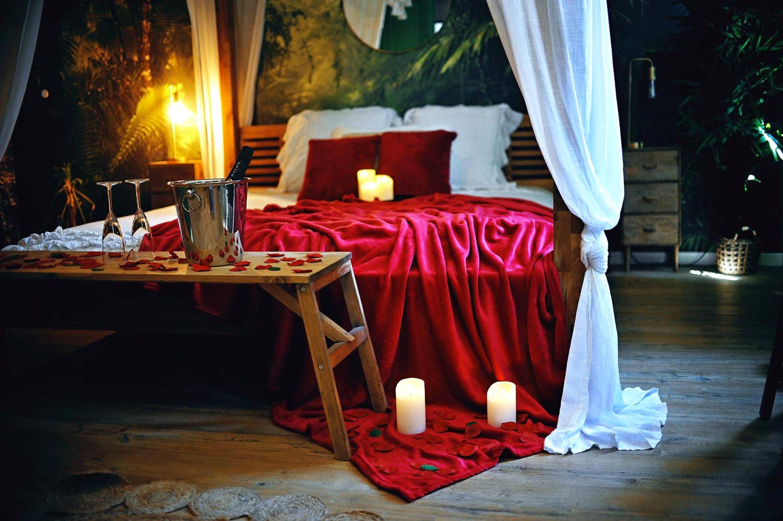 Lit à baldaquin avec jeté rouge et champagne - Love Room Évreux - L'Evasion romantique en Amazonie, SPA, Écran cinéma,...