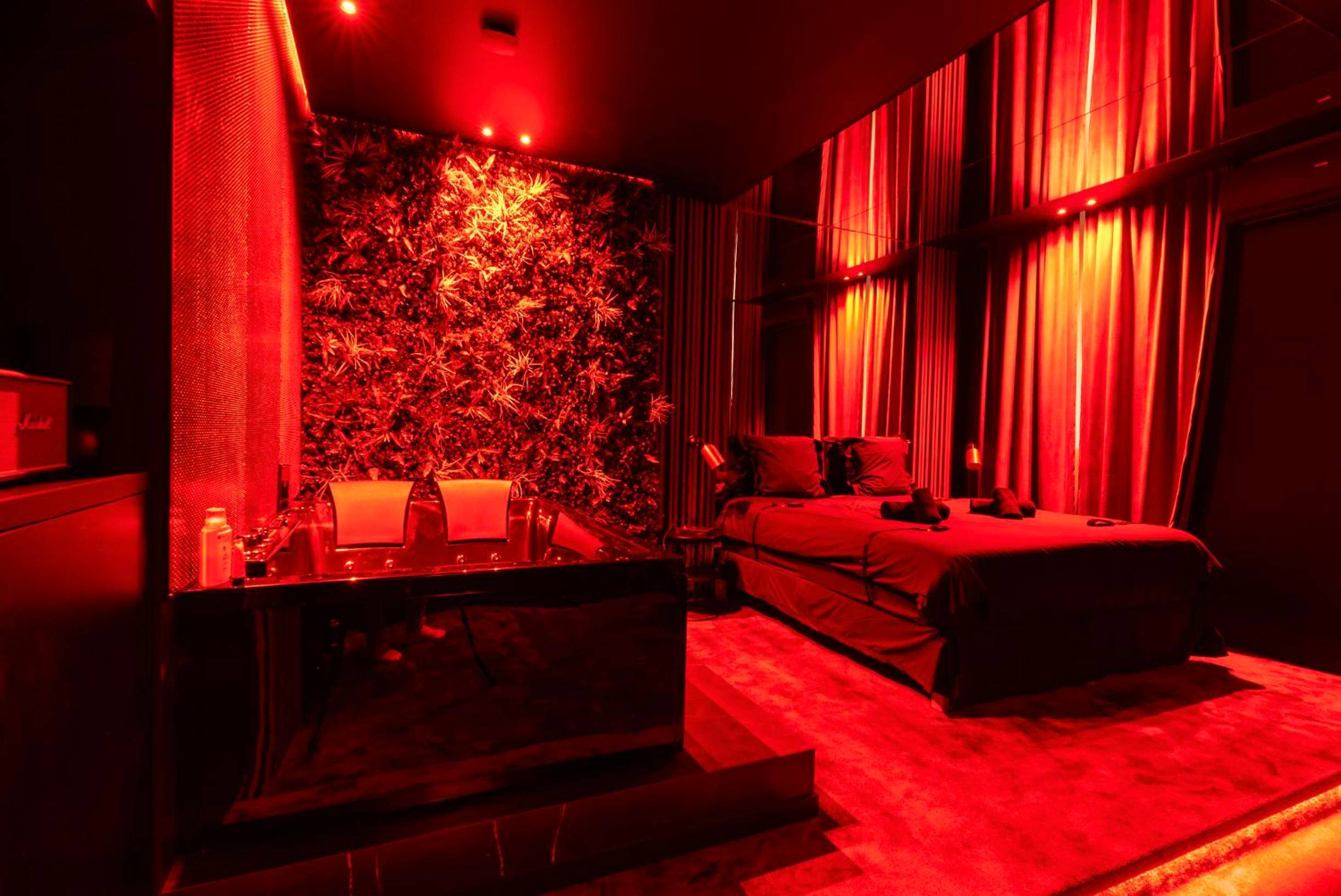 Jacuzzi et lit double sous lumière rouge - Love Room Cannes - Évasion intime : Love Room de luxe à Cannes