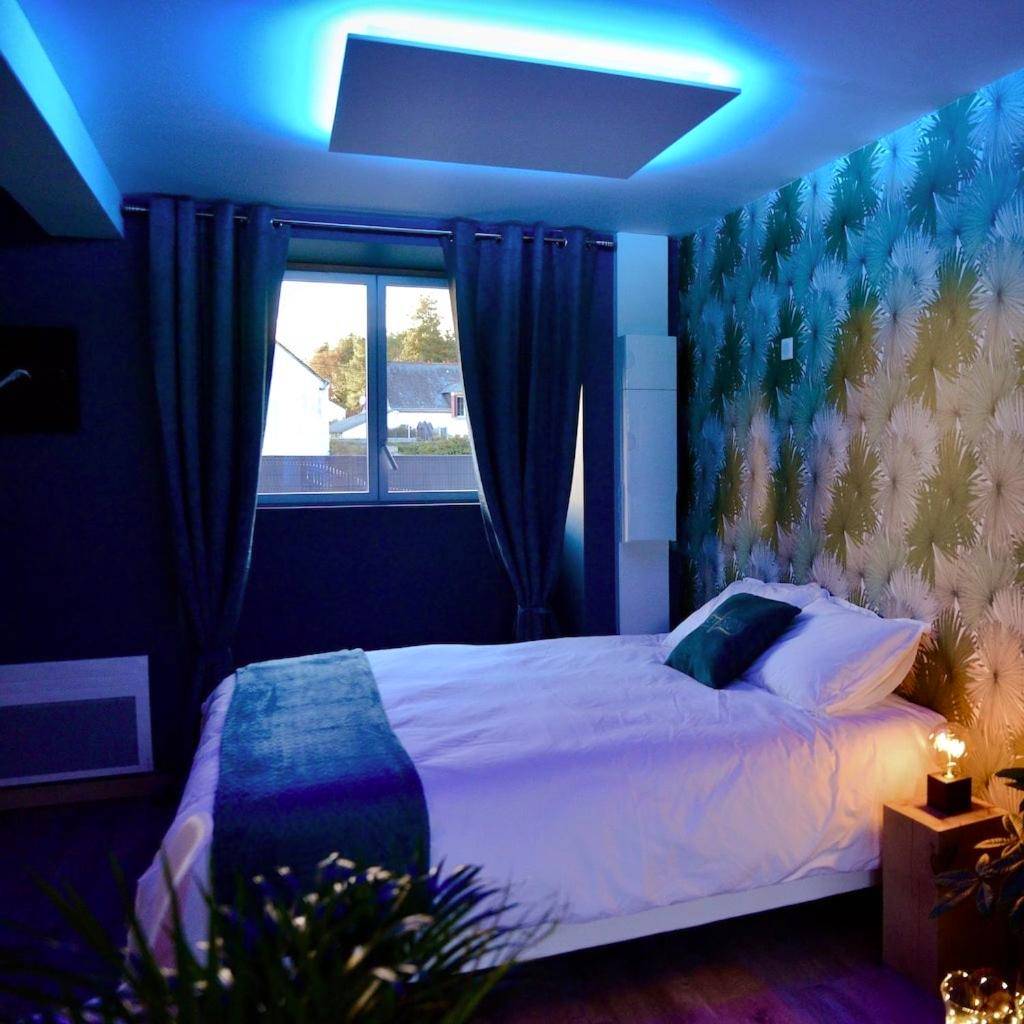 Lit double sous un éclairage néon bleu - L'Evasion chambre LAOS avec Jacuzzi privatif