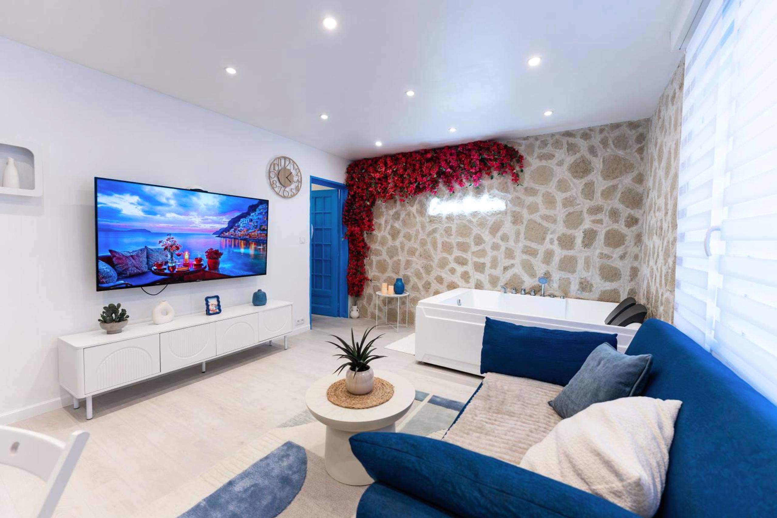 Salon moderne avec canapé bleu et jacuzzi - Évasion Santorin - Jacuzzi & Relax