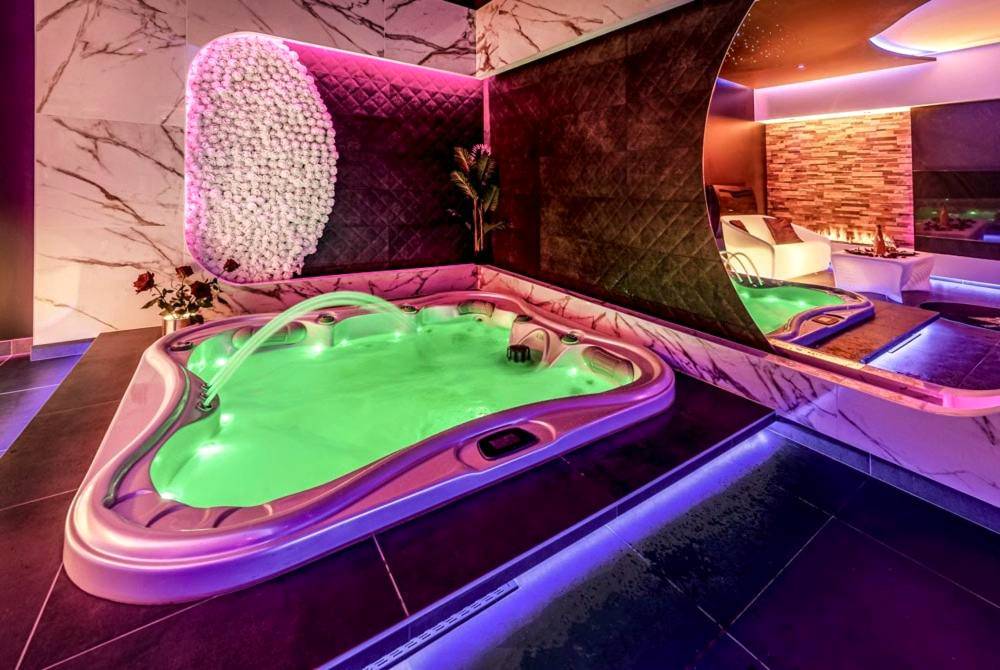 Jacuzzi privatif avec éclairage vert et rose - Love Room Fougères - Evasion sensuelle et charnelle SPA