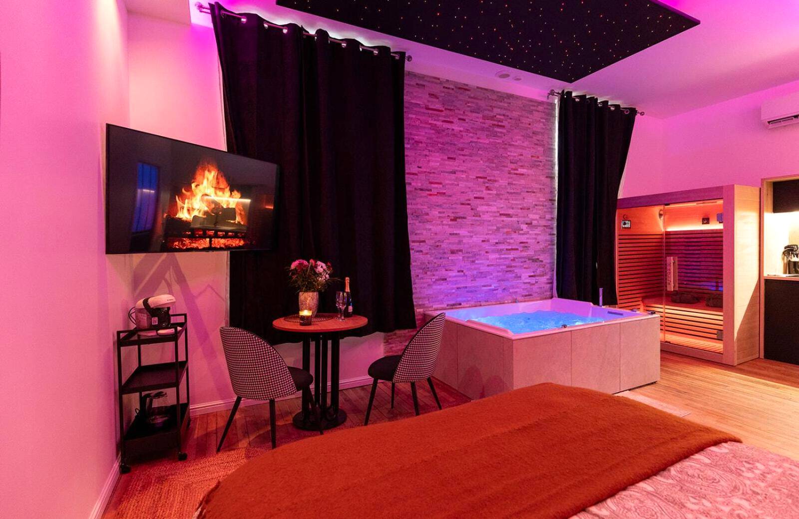 Vue d'ensemble de la suite avec jacuzzi et TV - Evasion Spa